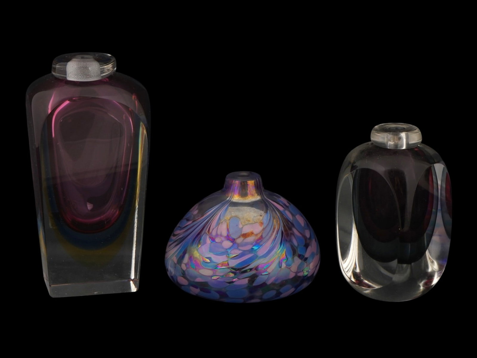 LOT OF AMERICAN AND ITALIAN MURANO ART GLASS VASES: A lot of three art glass wares, including two sommerso vases and one iridescent vessel. Two Murano art glass pieces feature thick walled clear glass encasing deep amethyst and smoke-grey cores, design