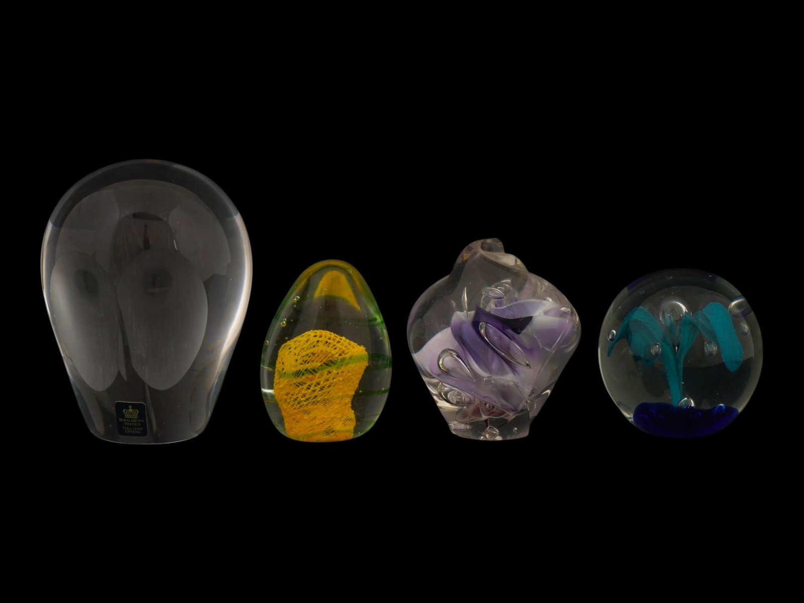 LOT OF VINTAGE ROYAL KRONA ART GLASS PAPERWEIGHTS: A lot of four vintage glass paperweights of various design. Transparent pieces with bubbles and color glass abstract shapes. The larges paperweight bears an etched mark on the bottom and an original R