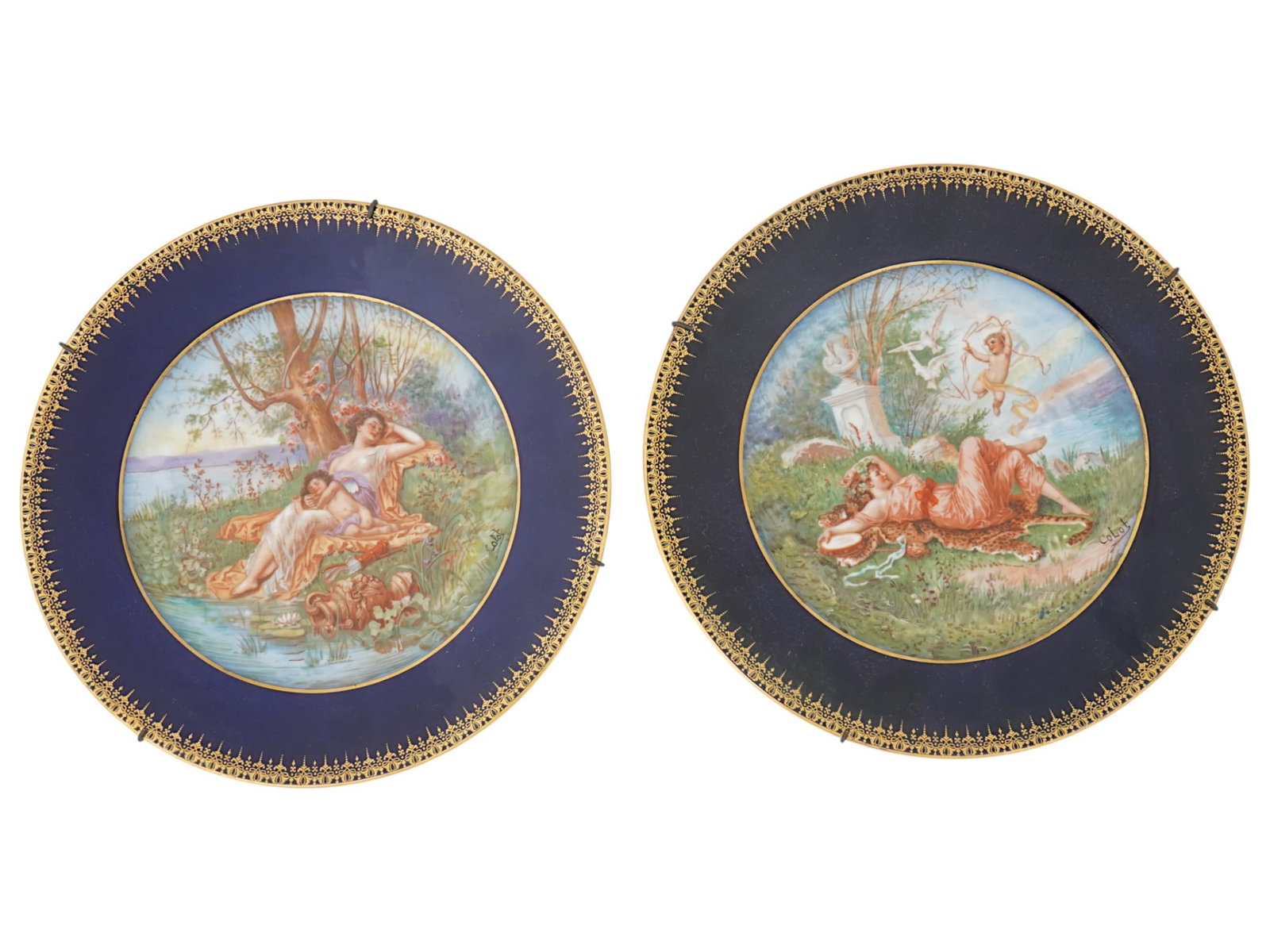 MICHELAUD FRERES LIMOGES PORCELAIN PLATES SIGNED: A pair of matching early 20th-century French hand-painted porcelain plates. Cobalt blue borders with gilt ornamental rims. The central parts depict Rococo scenes of nymphs with putti in landscape scen
