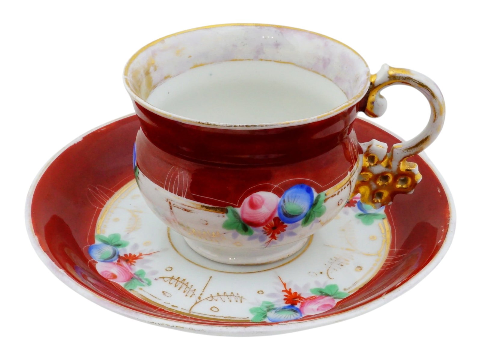 ANTIQUE RUSSIAN KUZNETSOV PORCELAIN TEACUP AND SAUCER: An antique Russian Kuznetsov porcelain teacup and saucer, dating to the late 19th century. Decorated with a rich ruby-red ground, hand-painted floral sprays, and elegant gilt accents. Marked on the bo