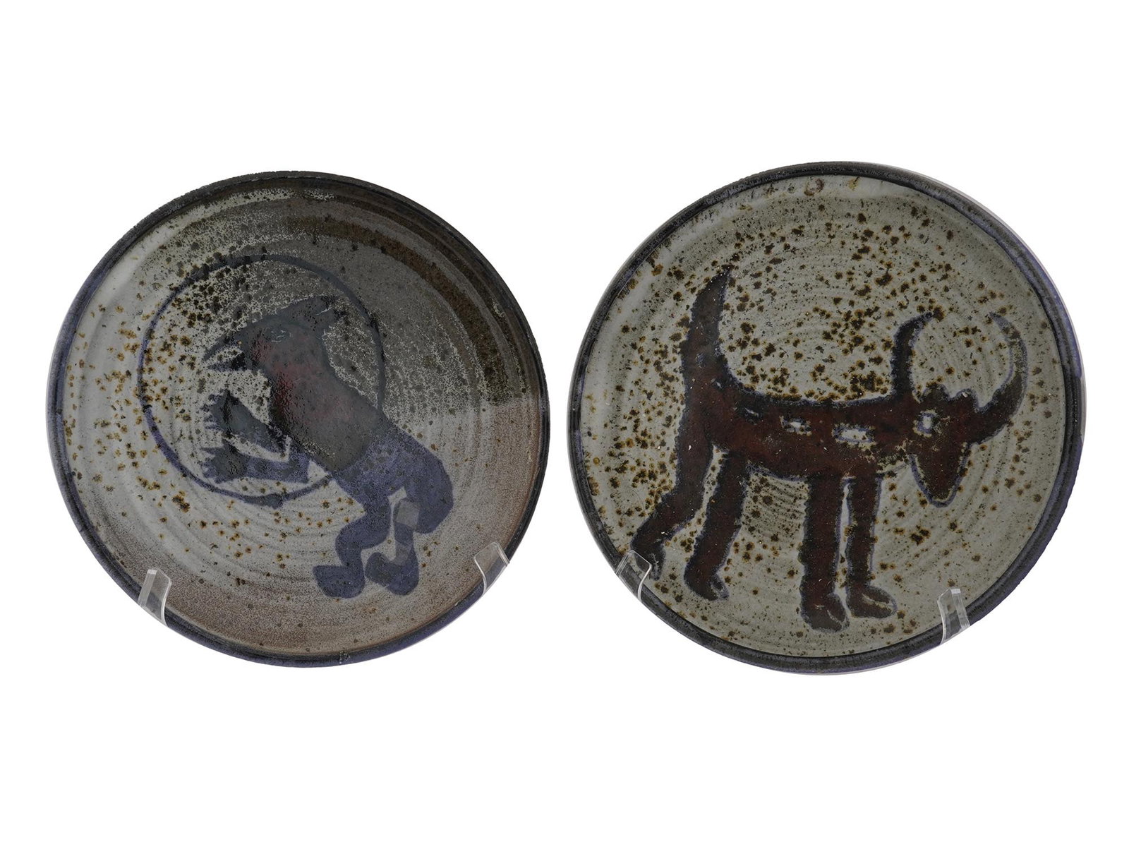 PAIR OF PRIMITIVE ARTISTIC GLAZED CERAMIC PLATES: A pair of vintage artistic glazed ceramic plates. The plates are covered with a glaze in blue, red, and white shades. The plates are adorned with a speckled design and adorned with hand painted images