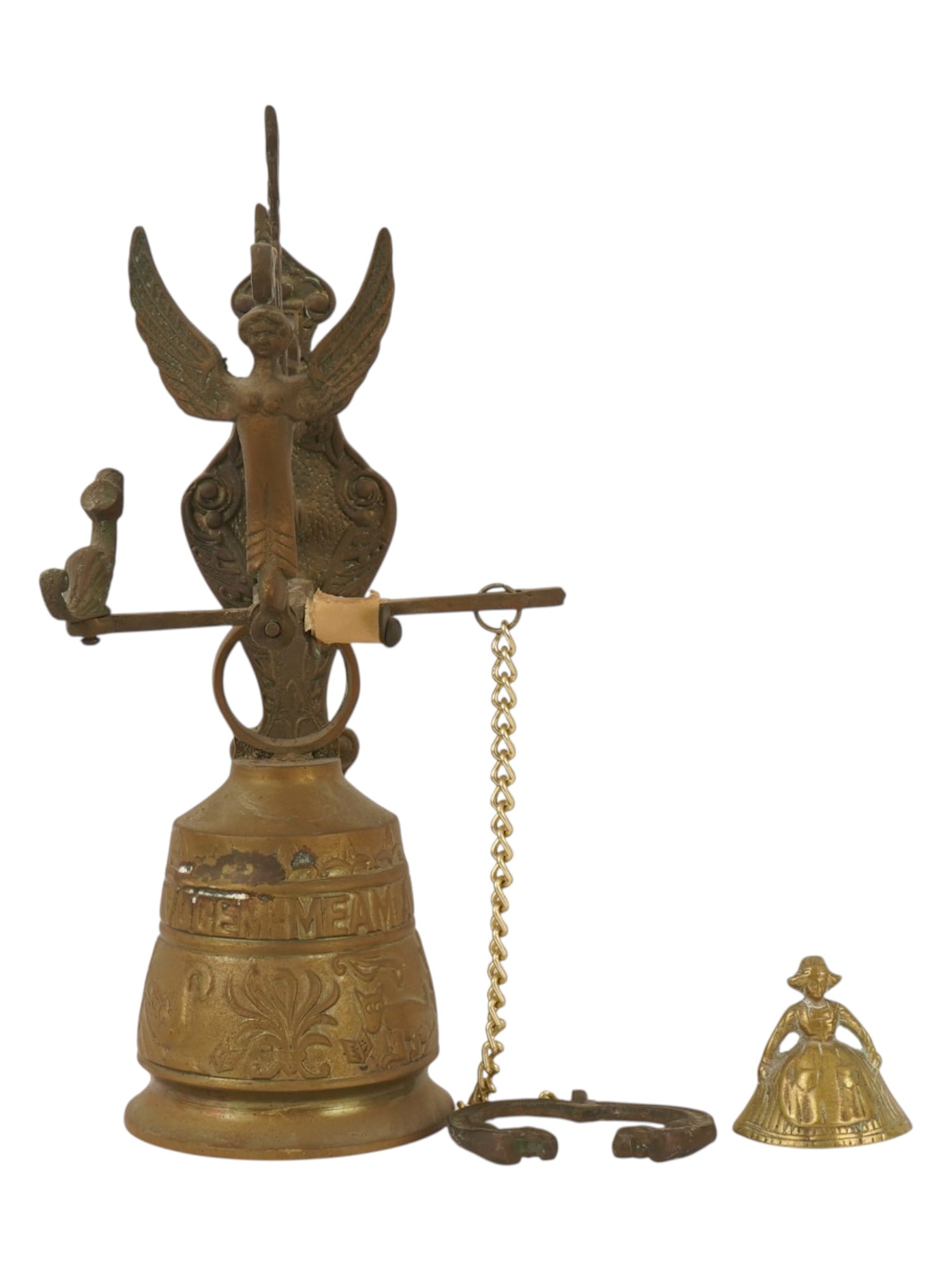 VINTAGE BRASS WALL BELL AND CRINOLINE LADY HANDBELL: Two vintage brass bells, including a monastery wall bell and a figural crinoline lady handbell. The wall bell features an ornate swing-arm mount with an angel figure, bird counterweight, and Latin ins