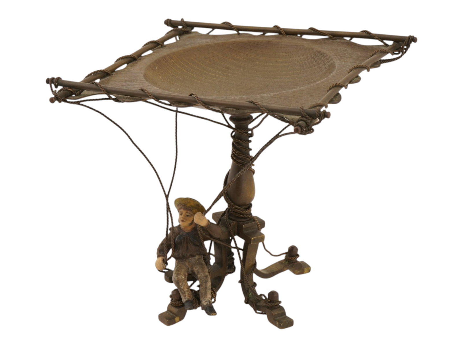 PATINATED BRONZE CENTERPIECE TAZZA W MAN FIGURINE: A patinated bronze centerpiece tazza. The ware features a square tray with a circular well, supported by a central columnar stem. The ware is decorated with a cast figure of a man at the base, rendere