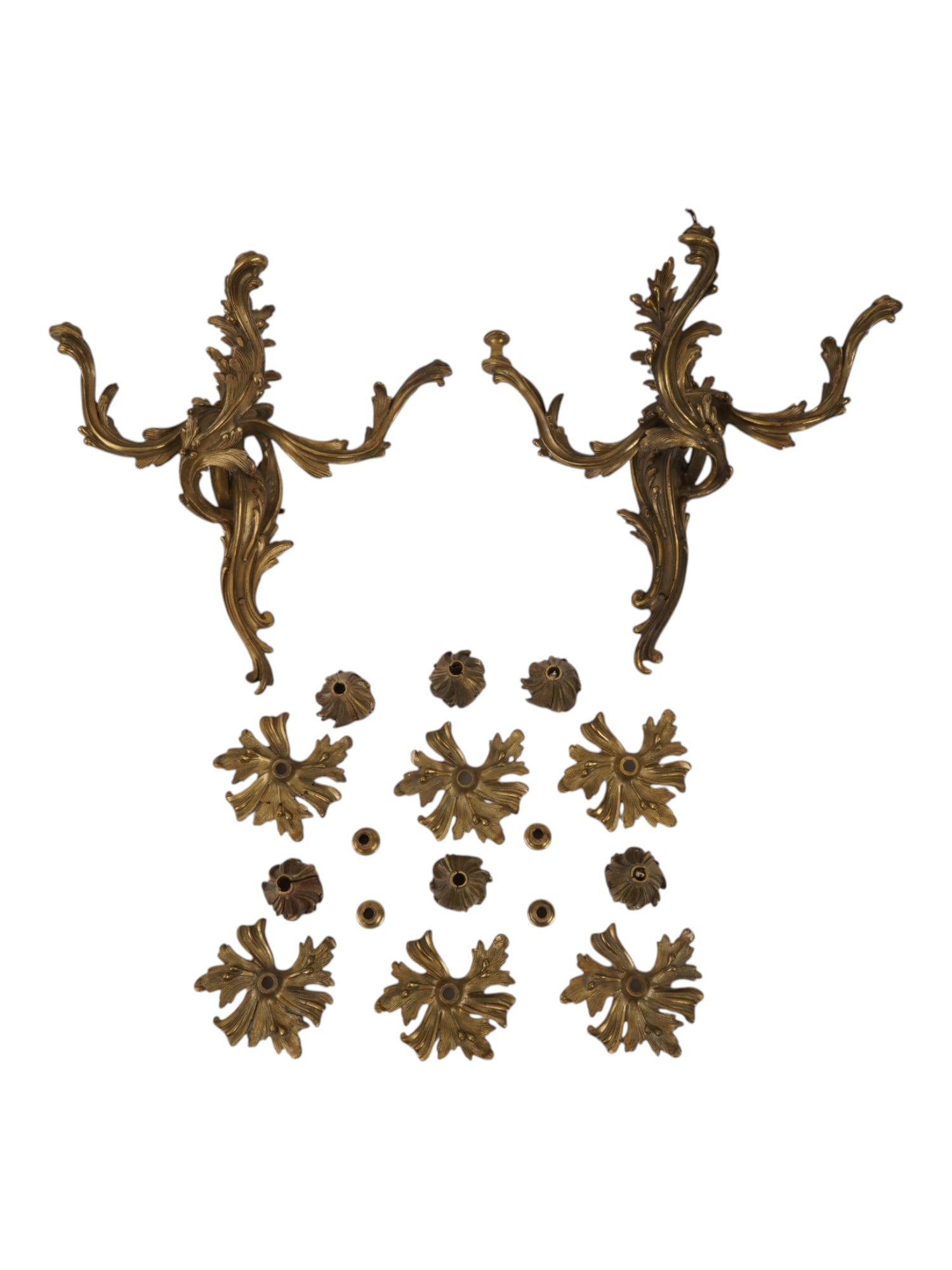 PAIR OF ANTIQUE FRENCH GILT BRONZE WALL SCONCES: A pair of antique French gilt-bronze wall sconces with their modular components. The set includes rocaille backplates and candle arms, floral bobeches, nozzles, spacers, and mounting hardware. Antique