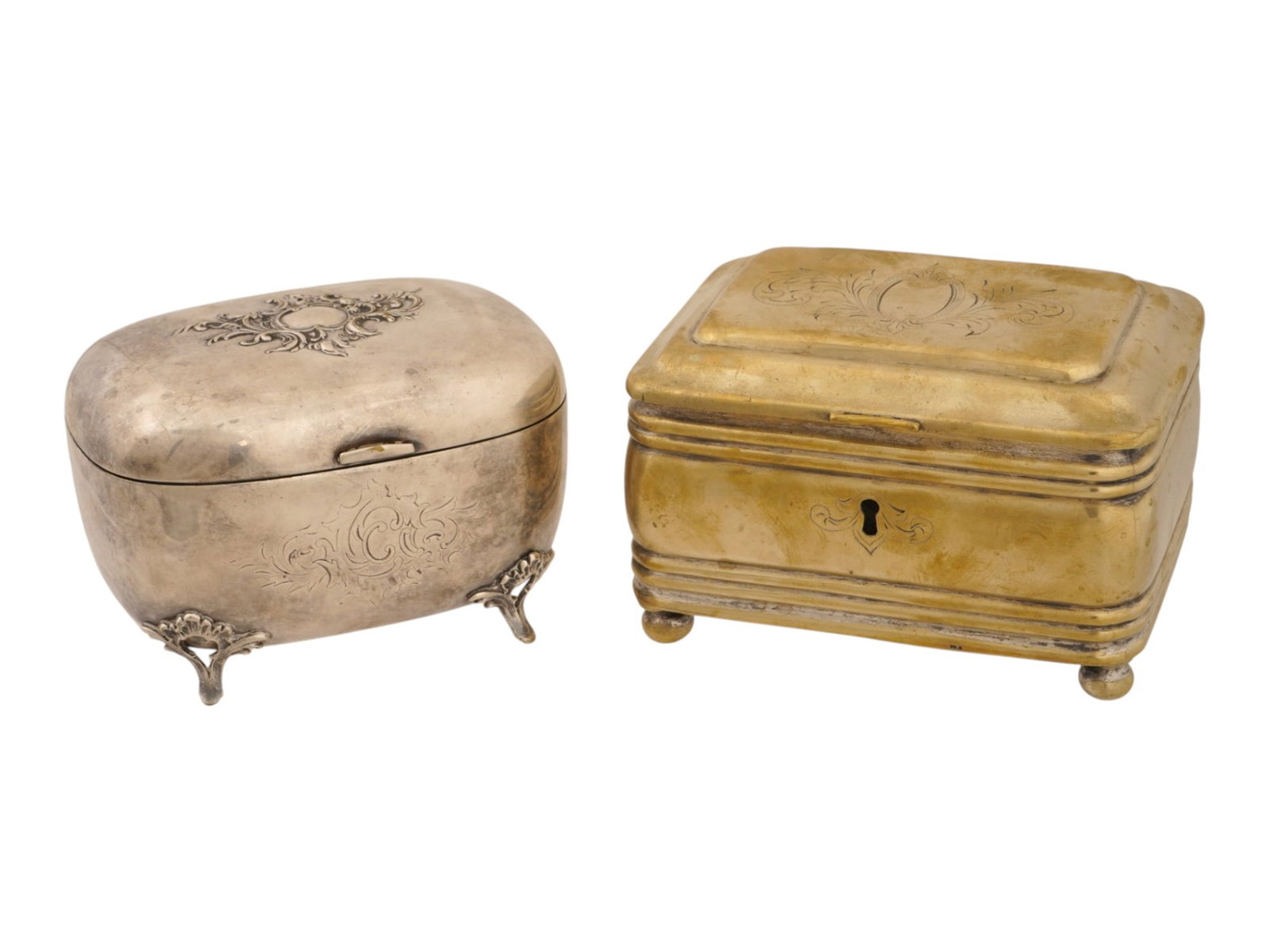 PAIR OF ANTIQUE JEWELRY BOXES WITH ENGRAVED DECORATIONS: A pair of antique jewelry boxes dating to the late 19th or early 20th century. The group includes an oval silver-tone casket on ornate Rococo-style feet with an engraved monogram and a rectangular bra