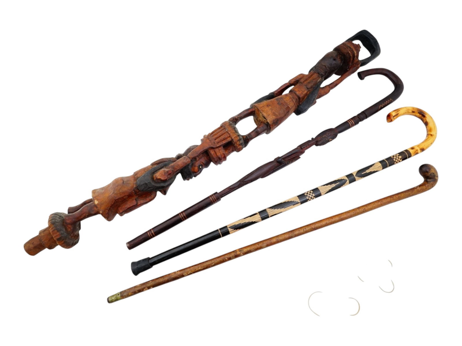 FOUR AFRICAN FIGURATIVE CARVED WOOD WALKING CANES: A group of four African figurative carved wood walking canes. The canes feature a variety of intricate designs featuring human heads and geometric patterns. Collectible Walking Sticks, Tribal Ethnic D