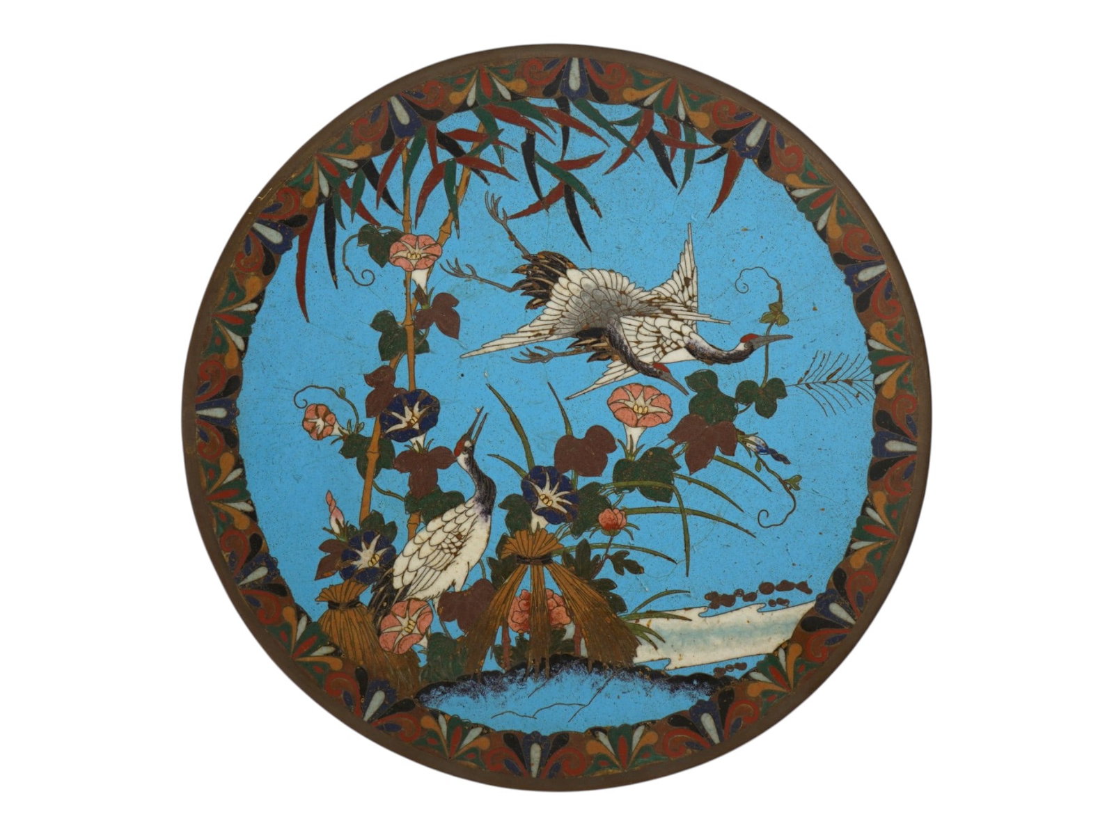 JAPANESE POLYCHROME DESIGN CLOISONNE ENAMEL PLATE: A Japanese decorative enamel over copper plate or charger. The interior of the plate is adorned with a polychrome design of three cranes in blossoming flowers and plants on the turquoise ground made