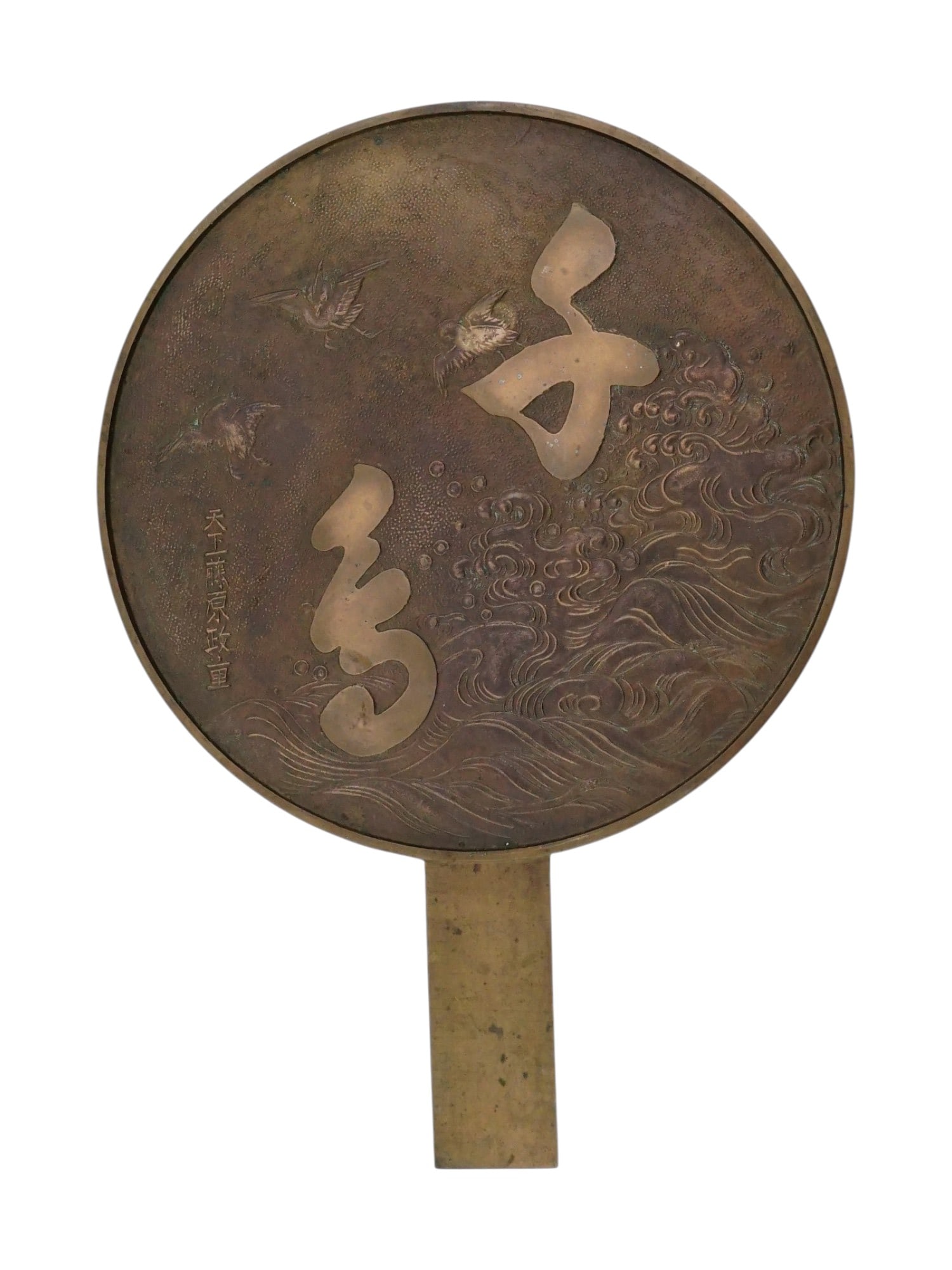 JAPANESE BRONZE HAND MIRROR BASE WITH INSCRIPTION: A Japanese bronze hand mirror base, known as an e kagami, features a circular form with an integrated rectangular handle and a reverse face decorated in relief. The design includes prominent calligrap