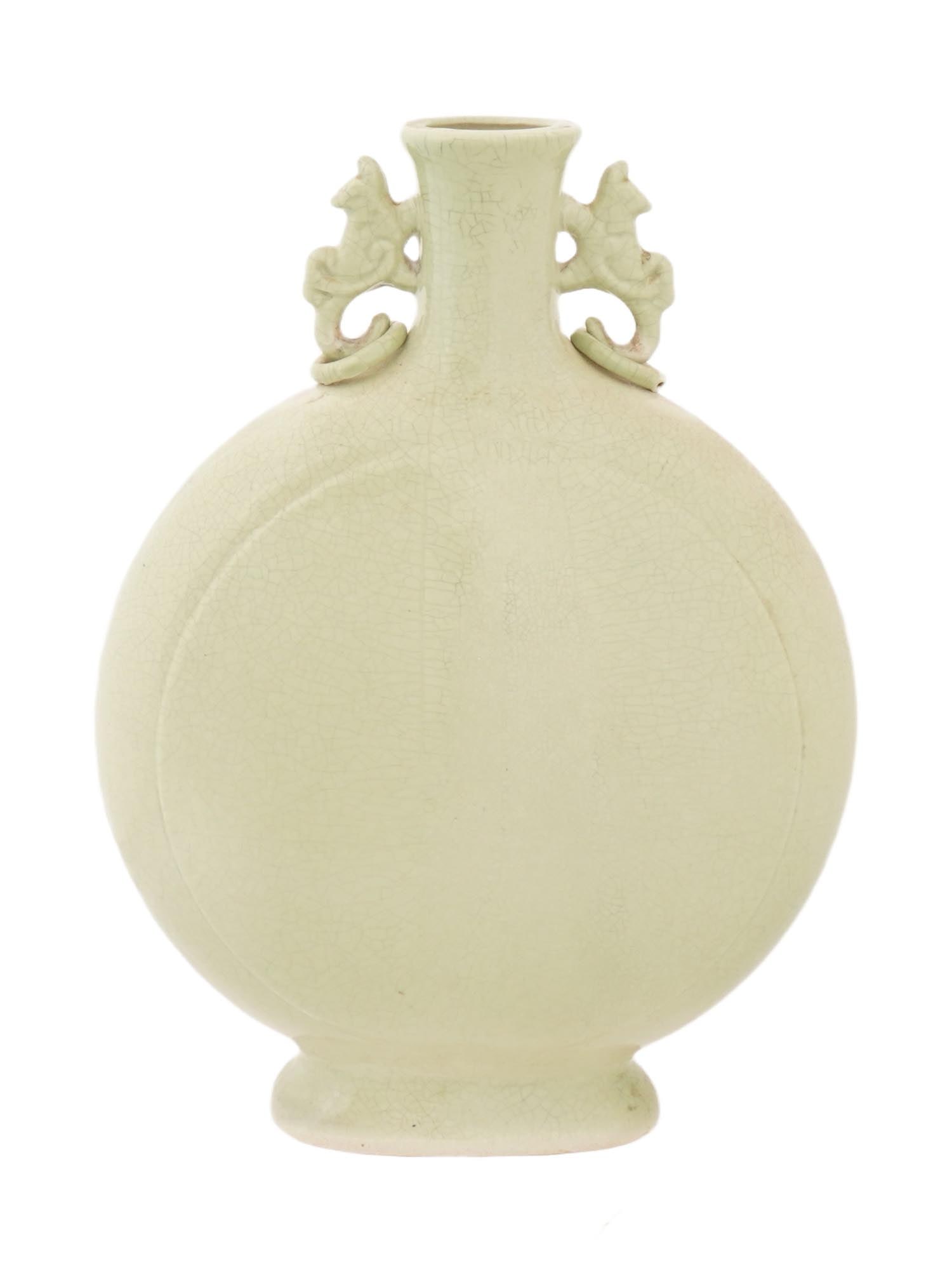 CHINESE CELADON CERAMIC DOUBLE HANDLED MOON FLASK: A Chinese celadon ceramic moon flask, characterized by its flattened circular body, a slender neck, two decorative zoomorphic handles, and a pale green glaze exhibiting fine craquelure. Collectible Or