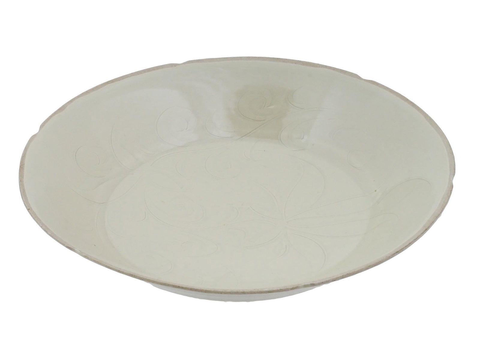 ANTIQUE CHINESE DING WARE GLAZED INCISED CERAMIC PLATE: An antique Chinese Ding ware glazed ceramic plate features a shallow, circular form with a distinctive foliated rim and a cavetto decorated with radiating fluted segments. The central medallion is inc