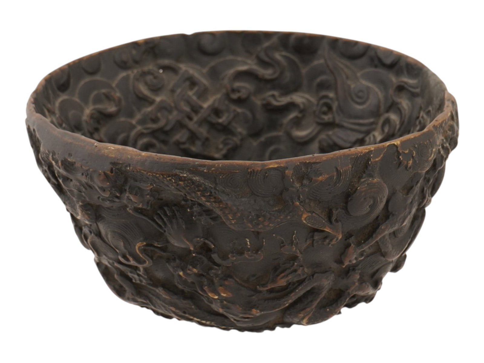 CHINESE DRAGON DESIGN DARK BROWN COMPOSITE BOWL: A Chinese dark brown composite bowl featuring dense relief decoration of writhing dragons amongst stylized clouds and scrolling waves. The motif extends from the exterior through to the interior well.