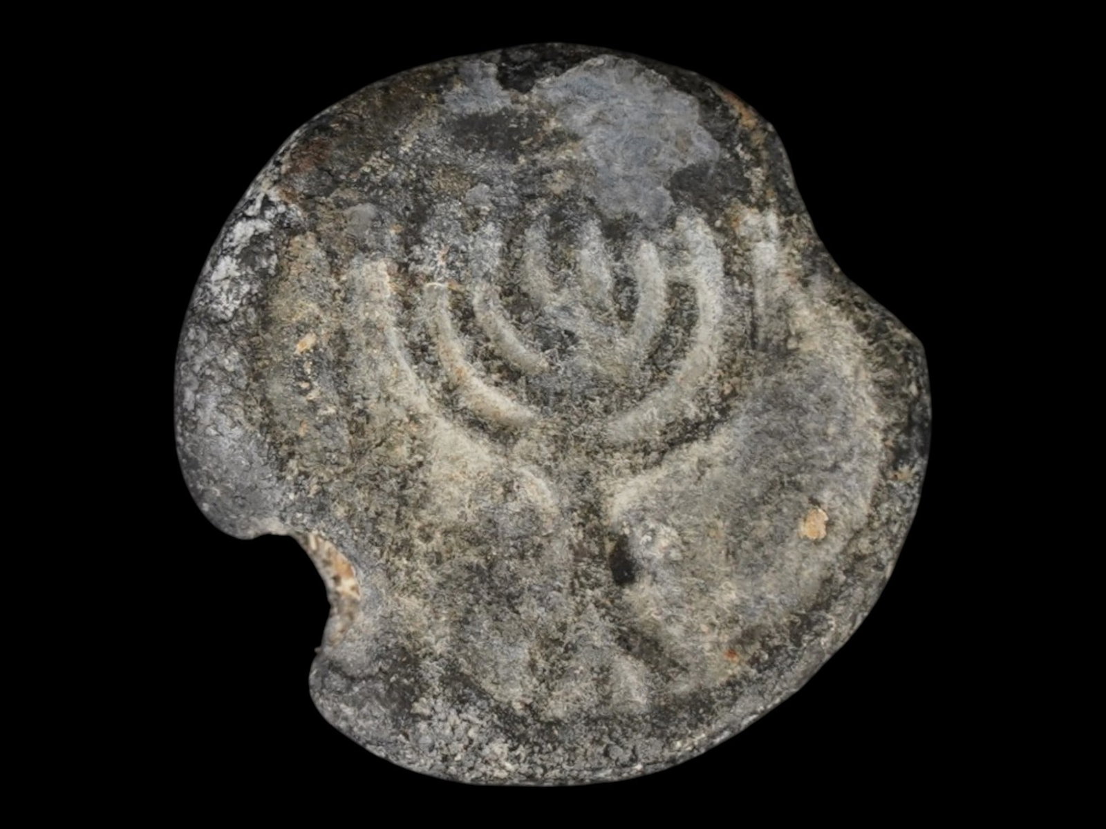 ANCIENT JUDAICA MENORAH LEAD SEAL 200 TO 400 AD: An ancient Judaica lead seal, dating to the Late Roman or Early Byzantine period between 200 and 400 AD. The obverse features a relief of the seven branched menorah, which served as a primary symbol o