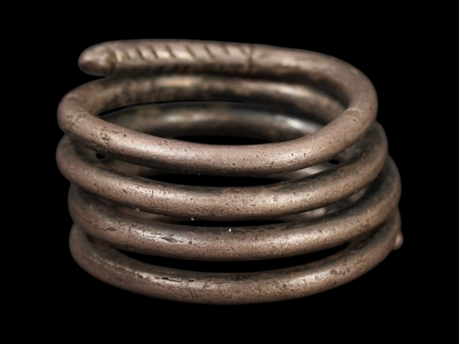 ANCIENT NEAR EASTERN SILVER RING IN THE FORM OF A SNAKE: An ancient Near Eastern silver ring in the form of a coiled snake, dating to the 2nd to 1st millennium BC. The serpent motif was widely revered in the ancient Near East, often symbolizing fertility, r