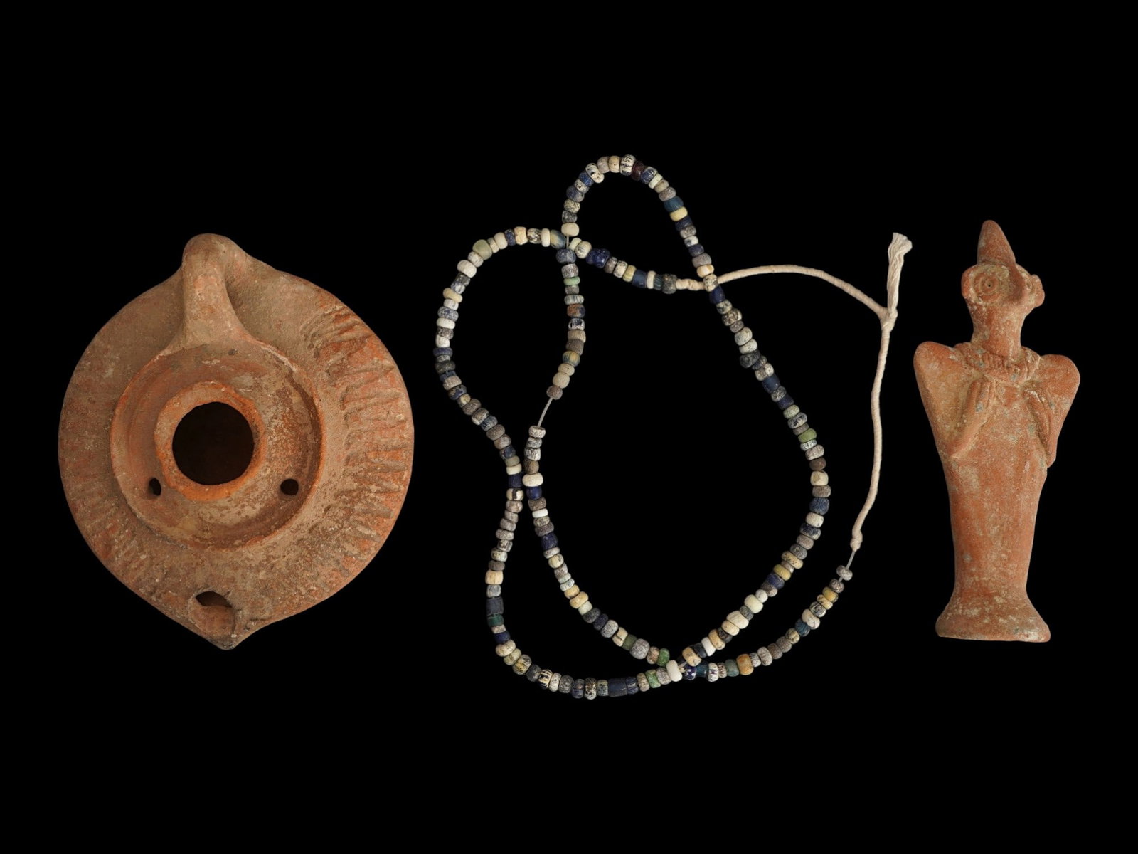 GROUP OF ANCIENT TERRACOTTA AND GLASS ARTIFACTS: A lot of three Ancient artifacts. First. A Hittite terracotta statue of the storm god and fertility god Baal. Dated 1st Millenium BC. Second. An Islamic terracotta oil lamp with relief ribbed pattern.