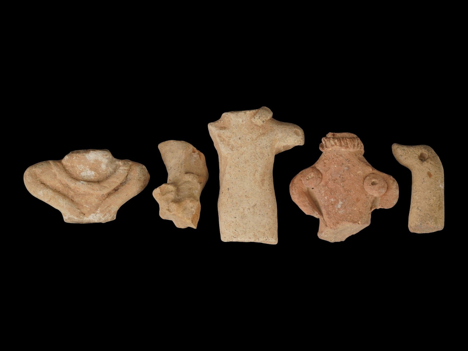 FIVE ANCIENT HITTITE TERRACOTTA FIGURINE FRAGMENTS: A group of five ancient Hittite terracotta figurine fragments. Circa 1600 to 1200 BC. The pieces are of various shapes, approximately the same size, and represent the upper parts of torso and limbs. A