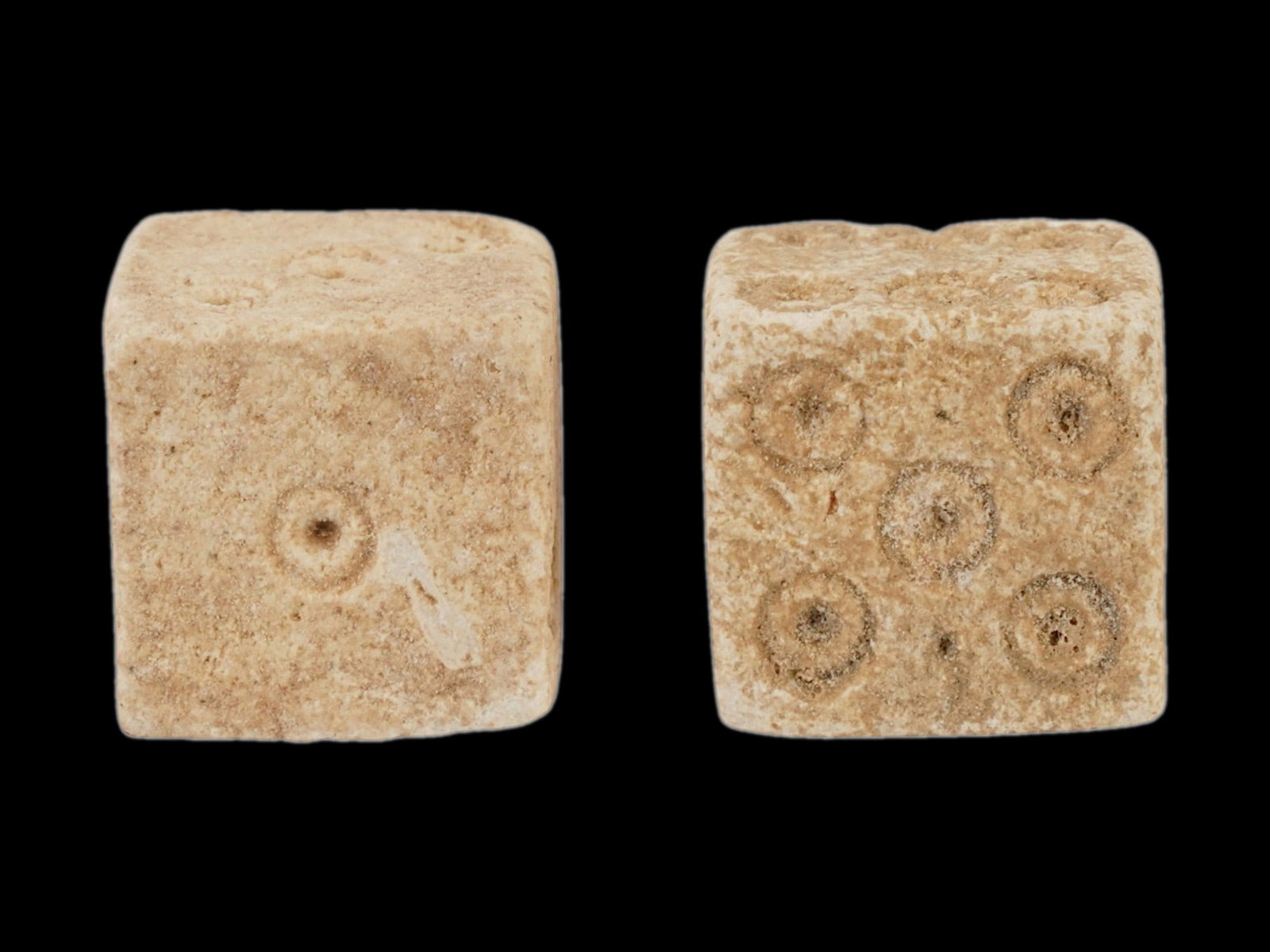PAIR OF ANCIENT ROMAN STONE DICE 100 TO 300 AD: A pair of ancient Roman hand carved stone dice, dating from 100 to 300 AD. These artifacts offer a tangible connection to the everyday life and leisure activities of the past. Carved from stone featur