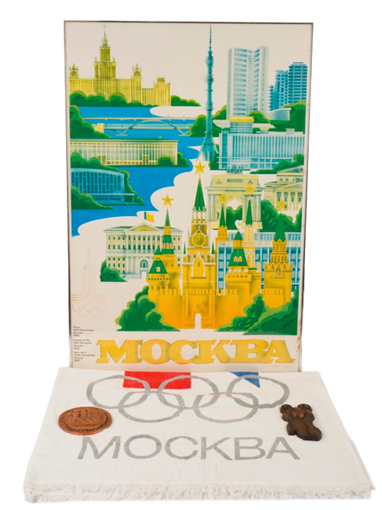 1980 MOSCOW OLYMPICS POSTER AND BRONZE BEAR AND BRASS PLAQUET AND TOWEL: A collection of vintage memorabilia from the 1980 Moscow Olympics. The lot includes a colorful poster of Moscow, a white towel with a colored Olympic related image and 1980 Olympics written on it, a b