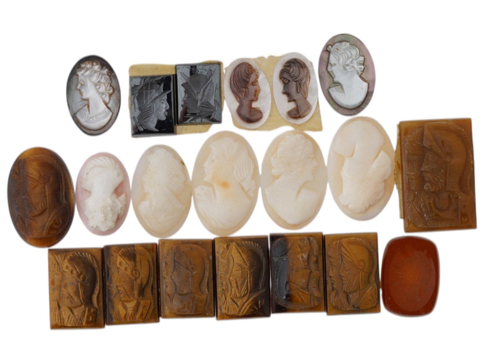 LOT OF ASSORTED PORTRAIT CARVED CAMEO MEDALLIONS: A large collection of assorted carved stone cameo medallions in various sizes and shapes. Each oval cut shell cameo depicts a relief female portrait in profile in the Victorian manner. The lot include
