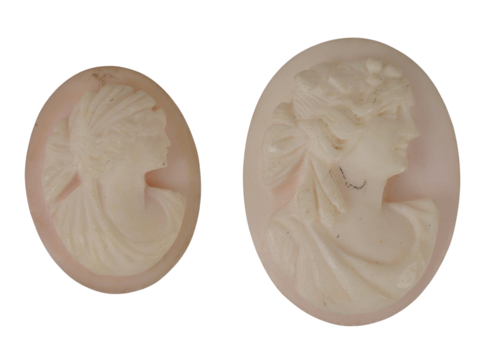 VINTAGE OVAL HAND CARVED SHELL CAMEOS W FEMALE PROFILES: Two vintage oval hand-carved shell cameos, each featuring a right-facing female profile in Victorian and Edwardian styles. The left figure wears a diadem, the right shows a floral chignon and carved d
