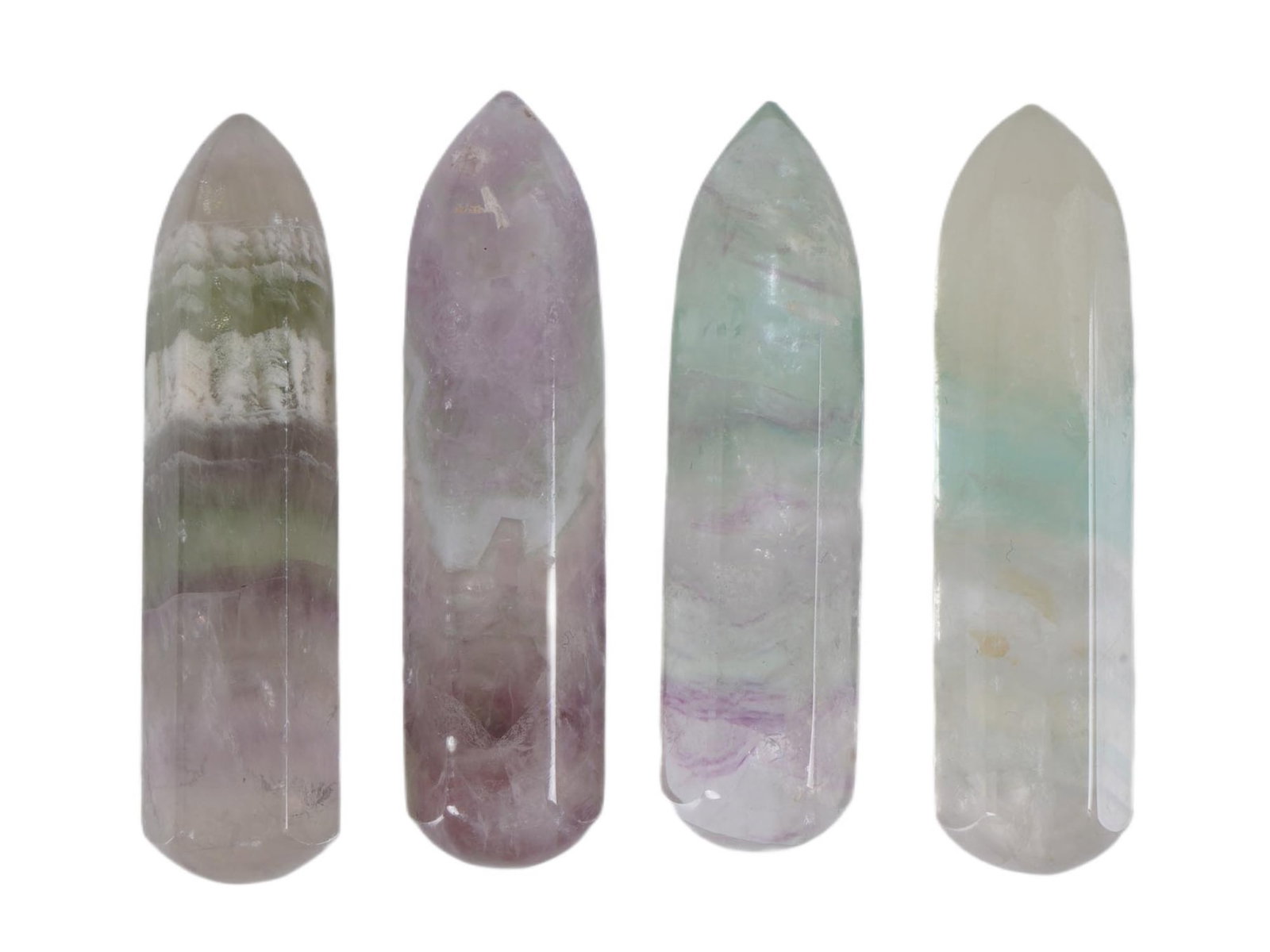 GROUP OF FOUR CARVED POINTED FLUORITE STONES: A group of four carved point fluorite stones. Shades of purple, green, light and blue are intertwined in unique patterns, creating a sense of harmony. Modern and Vintage Carved Natural Stones Figures,
