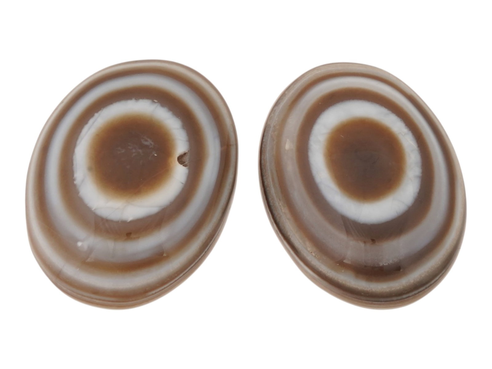 PAIR OF LARGE NATURAL BULLSEYE BANDED AGATE CABOCHON: A pair of large natural bullseye banded agate cabochons. The polished gemstones display a concentric eye pattern with alternating brown and white bands. Natural Gemstones And Jewelry Collectibles. THI