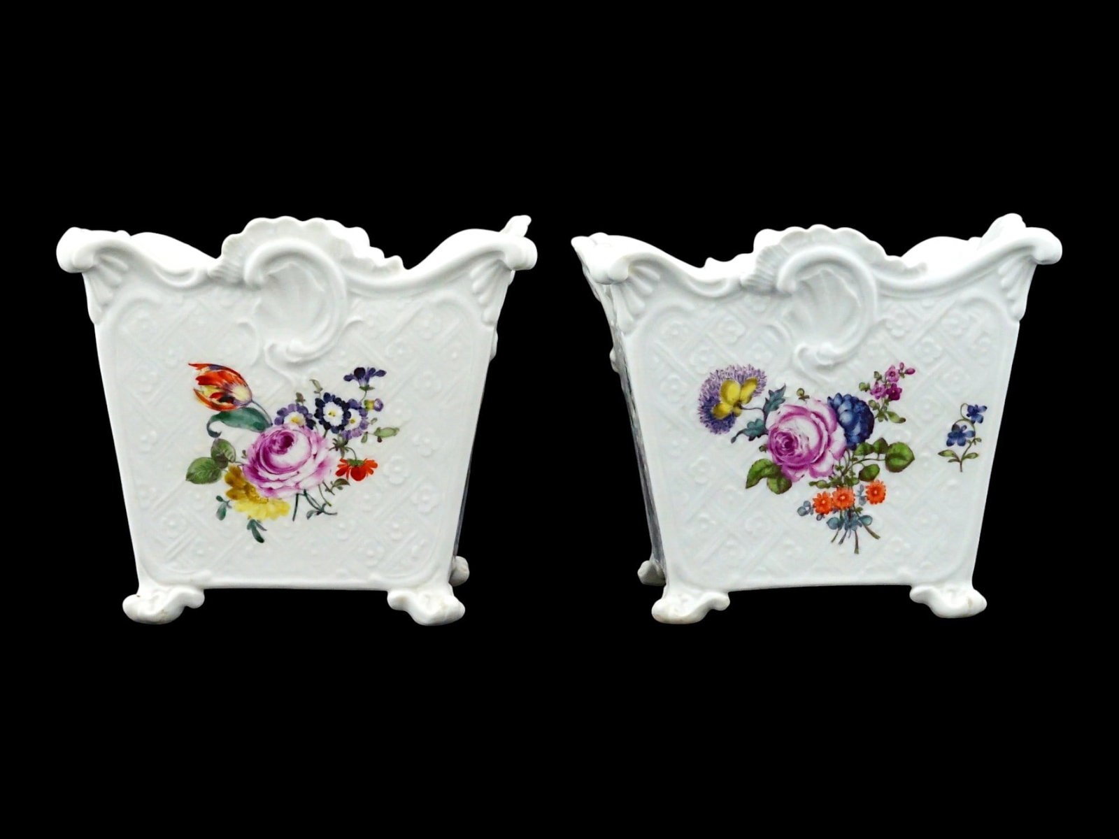 ANTIQUE MEISSEN HAND PAINTED PORCELAIN CACHEPOTS: A pair of antique Meissen porcelain cachepots, each featuring a flared scalloped rim, relief-molded lattice decoration, and four-footed roccaille base. The pieces are hand-painted with polychrome Deut