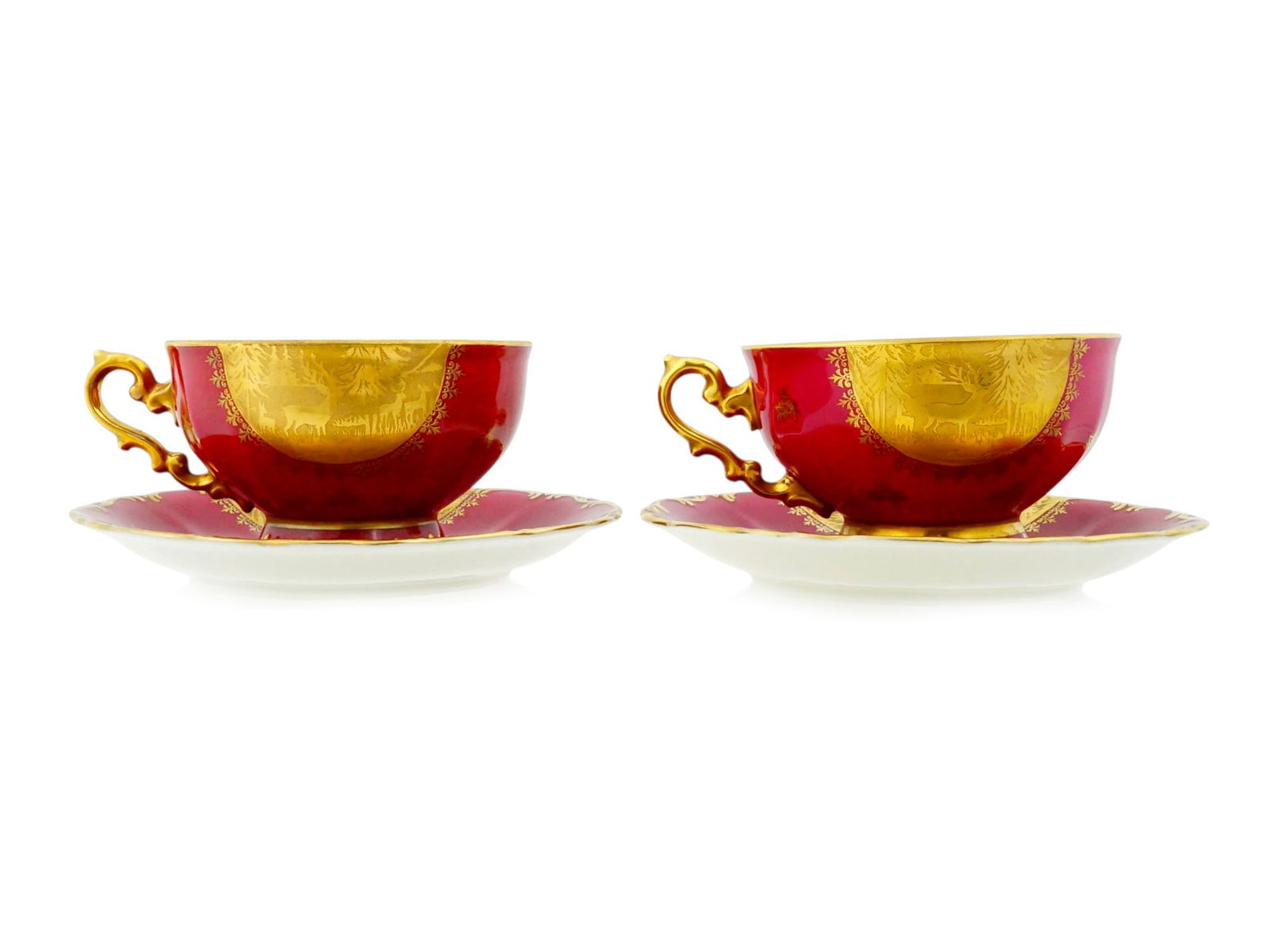 PAIR OF CZECH ACID ETCHED PORCELAIN TEA CUPS SAUCERS: A pair of Czechoslovakian porcelain tea cups and matching saucers. Each cup features a deep ruby red ground decorated with elaborate acid etched gilding. Each piece showcases a central raised gold pan
