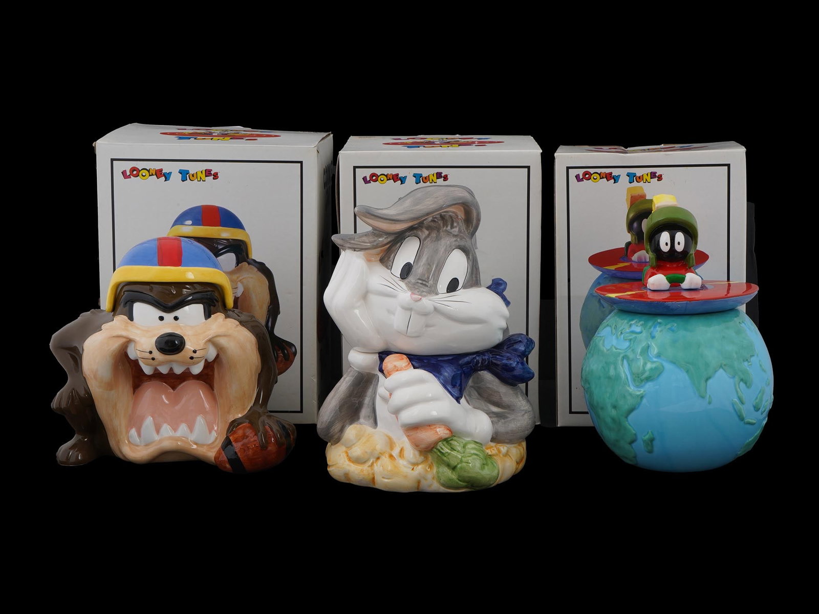 LOT OF AMERICAN CARTOON COVERED CERAMIC COOKIE JARS IOB: A lot of three American cartoon covered ceramic cookie jars. Each is made in a figural design representing Looney Tunes cartoon characters including the Tasmanian Devil wearing a sports helmet, Bugs B