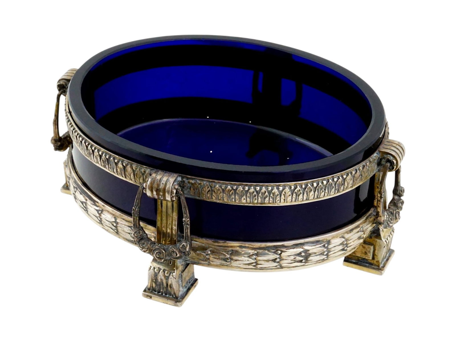 GERMAN M J RUKERT COBALT BLUE AND SILVER CENTERPIECE: A late 19th century German centerpiece. The ware features a removable oval cobalt blue glass liner set within a pierced 800 silver mount by M.J. Rukert. The Neoclassical design incorporates four archi
