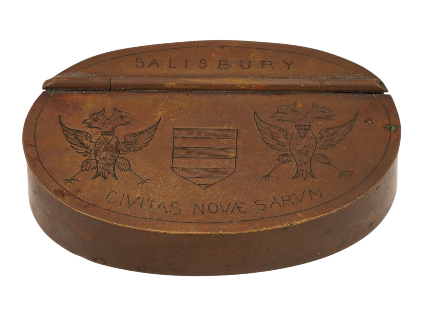 ANTIQUE BRITISH SALISBURY BRASS TOBACCO BOX: An antique mid to late 19th-century British brass tobacco or snuff box. Oval piece. The hinged lid is engraved with two eagles, a crest, and inscription Salisbury, Civitas Novae Sacrum, the city's mot