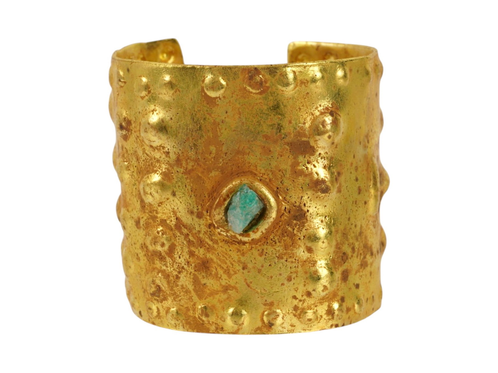 ANCIENT PRE COLUMBIAN TUMBAGA GOLD CUFF BRACELET: An ancient Pre Columbian wide cuff bracelet, crafted from tumbaga, a traditional Pre Columbian gold and copper. The bracelet is made in a repousse design and encrusted with a green stone to the center