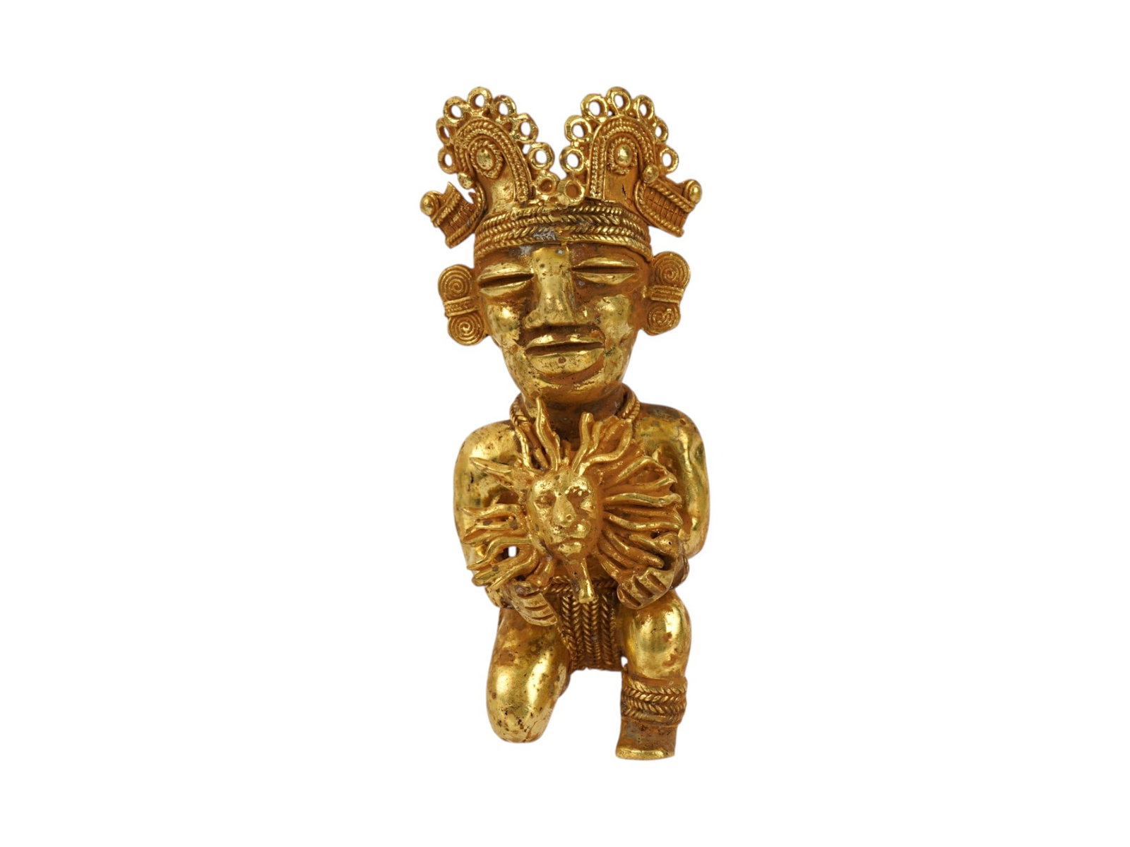 PRE COLUMBIAN TAIRONA TUMBAGA SHAMAN FIGURINE: An ancient Pre Columbian Tairona tumbaga figurine representing a crowned shaman holding the sun. Tumbaga, an alloy of gold and copper, showcases the metallurgical proficiency of Pre Columbian Mesoamer