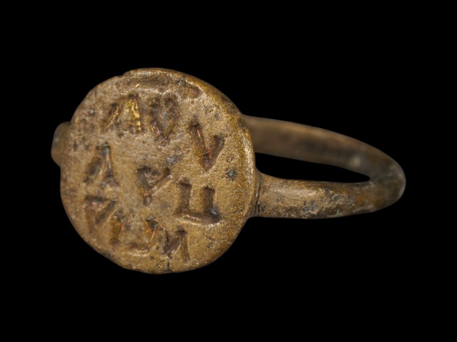 ANCIENT LATE ROMAN OR BYZANTINE BRONZE RING: An ancient Late Roman or Byzantine bronze ring, circa 200 to 400 AD, featuring a bezel inscribed with three lines of text. Such rings often served devotional, ceremonial, or protective purposes, with 