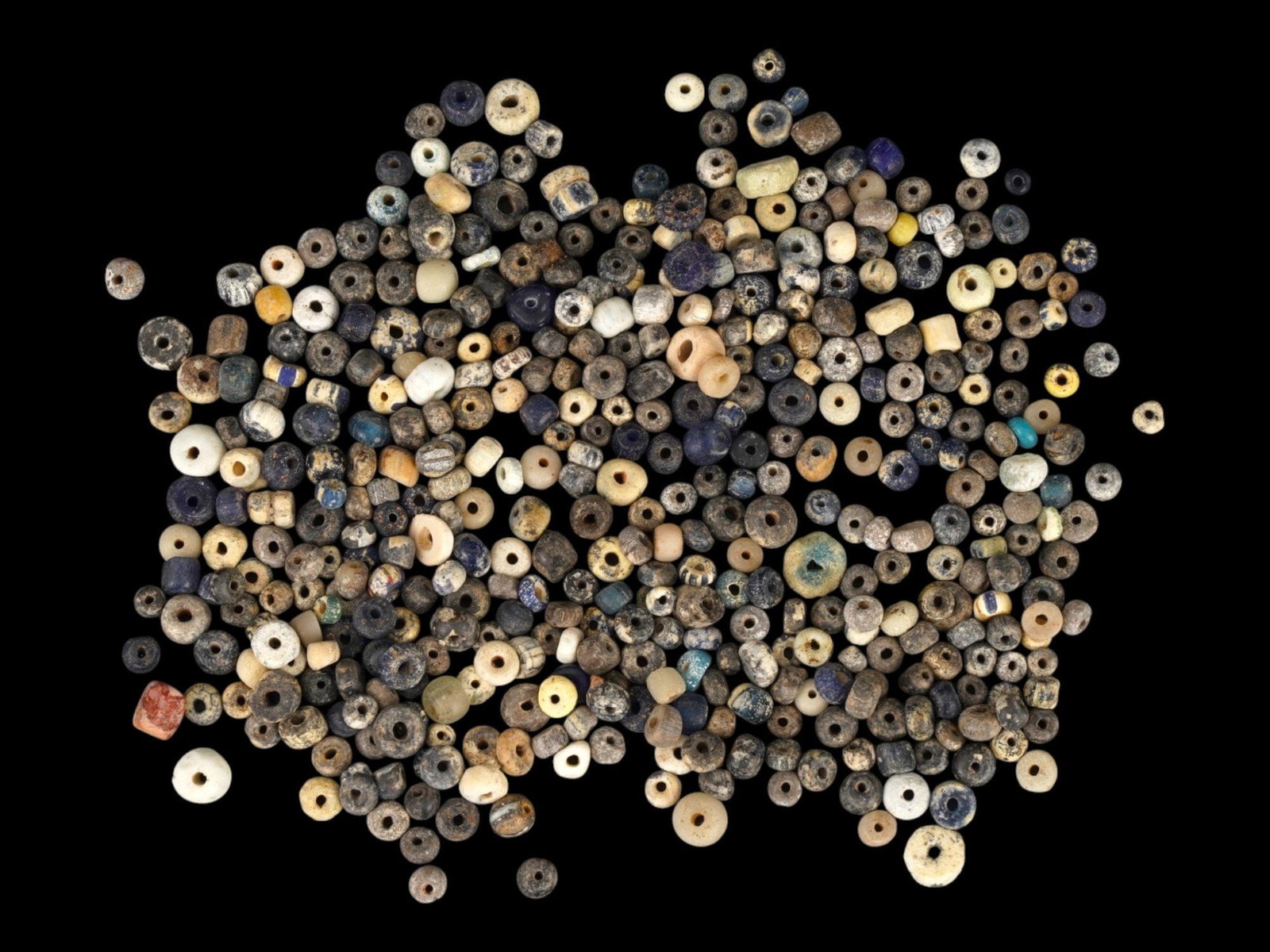 GROUP OF ANCIENT ROMAN GLASS BEADS 100 TO 300 AD: A collection of assortment of Roman glass beads dating from approximately 100 to 300 AD. The group features a variety of polychrome and monochrome specimens in hues of cobalt blue, amber, emerald gree