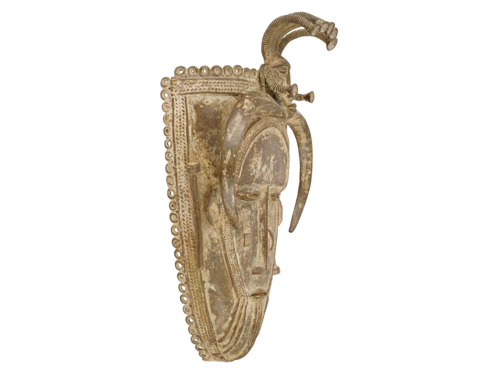 AFRICAN SENUFO KPELIE BRONZE MASK FROM THE IVORY COAST: An African Senufo Kpelie mask from the Ivory Coast, traditionally cast in bronze or brass using the lost-wax method. These masks serve as vital sacred objects within the Poro society, a male-only soci