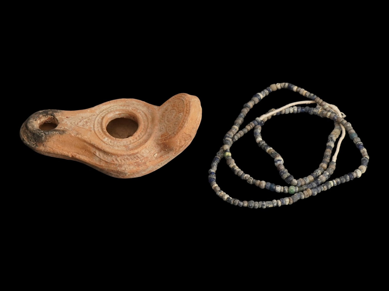 ANCIENT HOLY LAND BEADED NECKLACE AND OIL LAMP: A pair of Ancient Holy Land artifacts. Ca. 100 to 400 AD. A glass beaded necklace. A terracotta oil lamp adorned with a galaxy design. Historical Finds And Archaeological Relics, Jewelry And Accessori