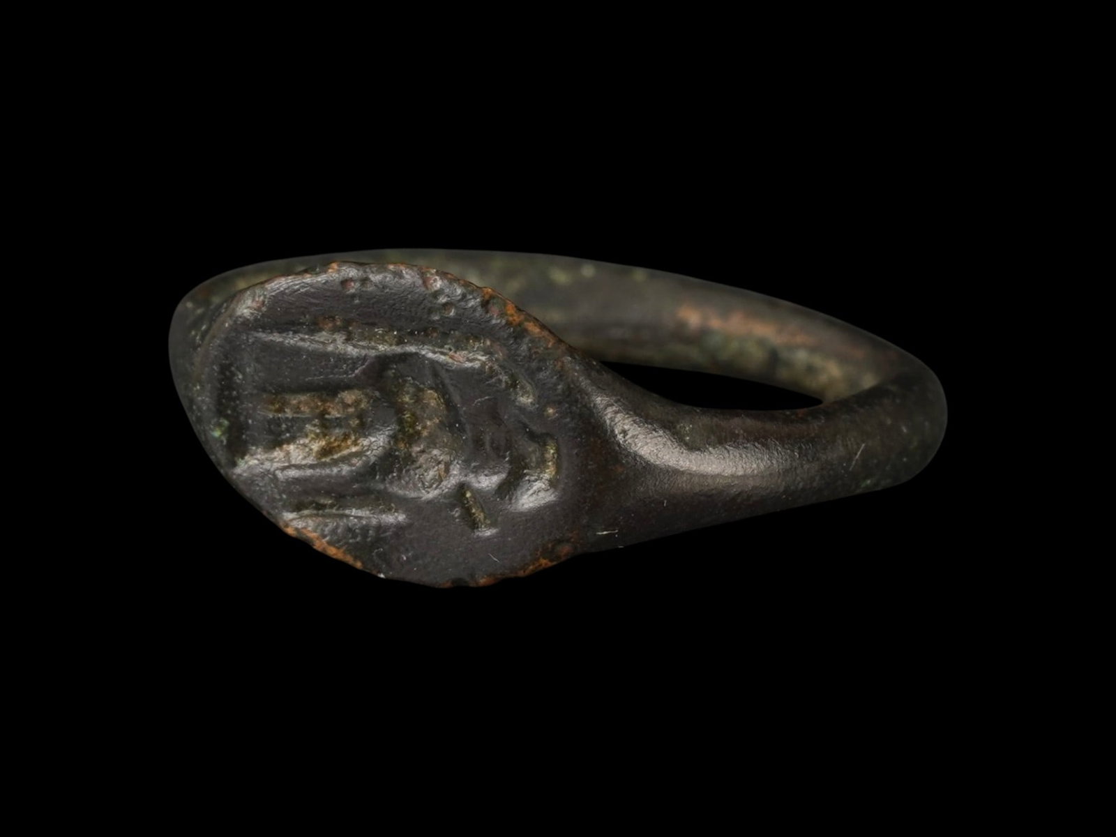ANCIENT GRECO ROMAN BRONZE SIGNET RING 200 BC TO 100 AD: An ancient Greco Roman bronze signet ring with flattened oval bezel. Circa 200 BC to 100 AD. The intaglio engraved decoration depicts a standing figure, presumably a Zeus. Archaeological and