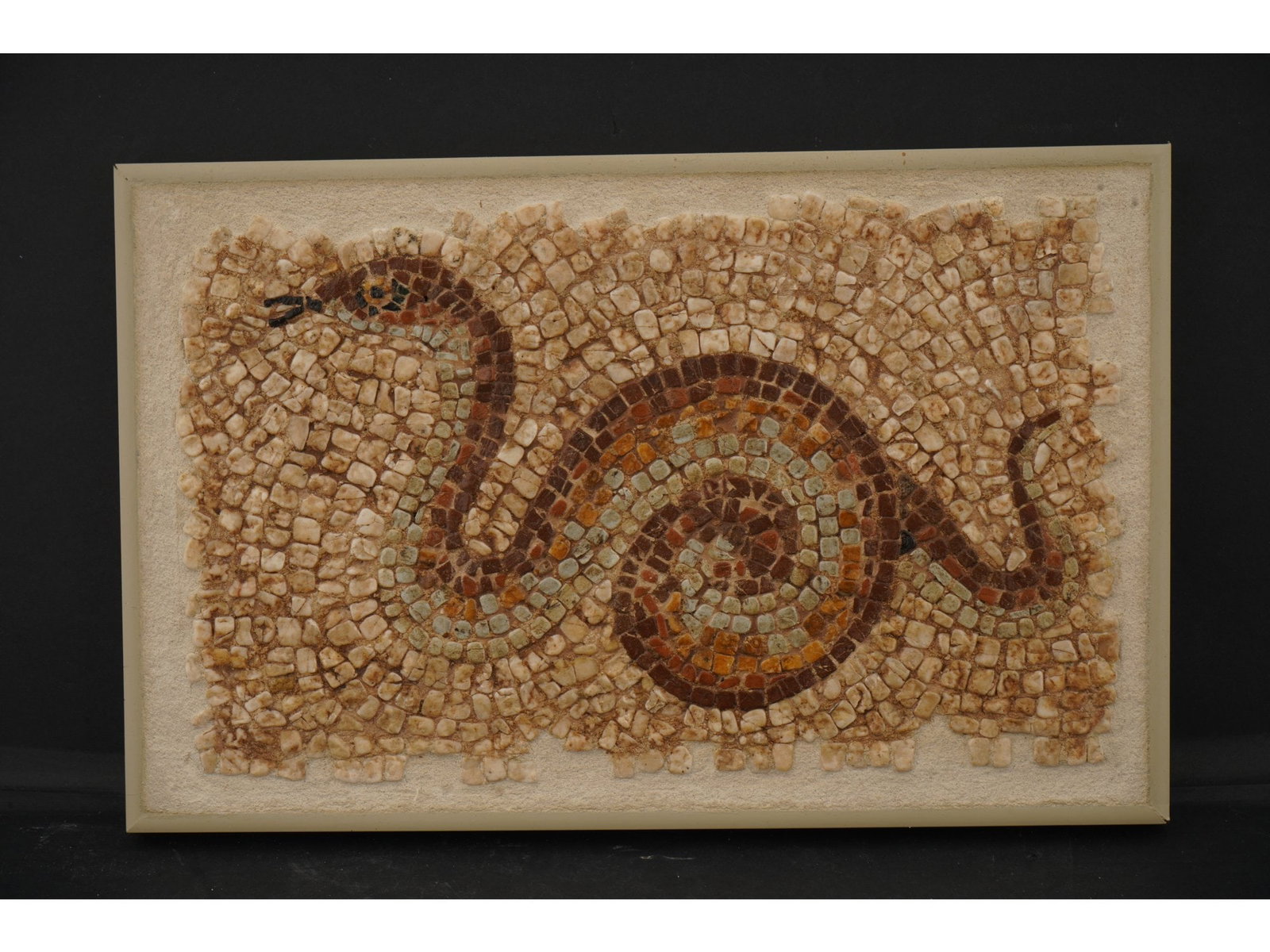 ANCIENT ROMAN MOSAIC FRAGMENT OF A SNAKE: An ancient Roman mosaic fragment depicting a snake, dating from approximately 100 to 300 AD. Composed of hand-set stone tesserae, the mosaic reflects the craftsmanship and decorative traditions of the