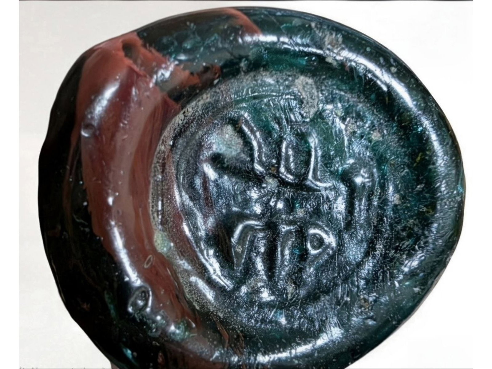 ANCIENT ISLAMIC GLASS SEAL WITH ARABIC INSCRIPTIONS: An ancient Islamic inscribed glass seal, dating from approximately 600 to 800 AD. The seal bears Arabic inscriptions reading Allah and Muhammad and exhibits the characteristic translucent surface and 