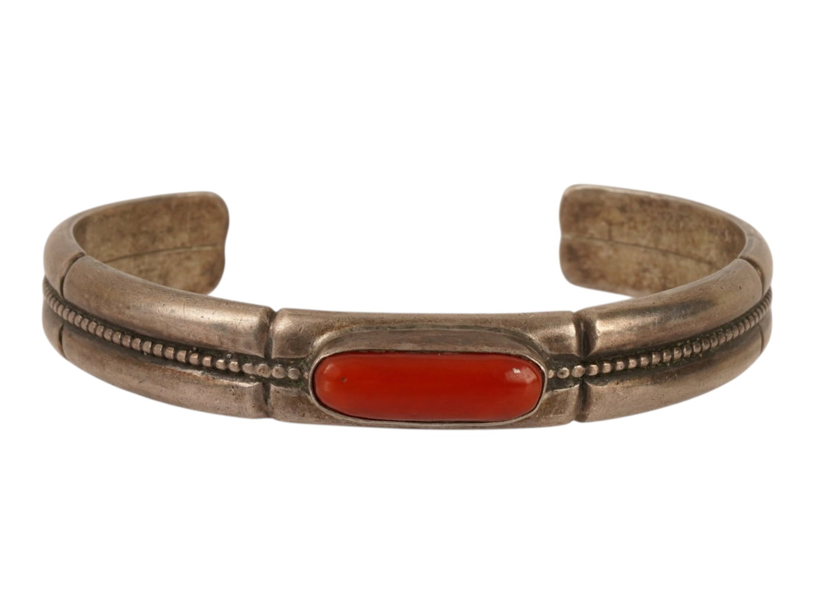 VINTAGE AMERICAN STERLING SILVER CORAL CUFF BRACELET: A vintage American Navajo or Zuni style stamped sterling silver and red coral stacker cuff bracelet. The bracelet features a central rectangular red coral cabochon in a smooth bezel, accented by