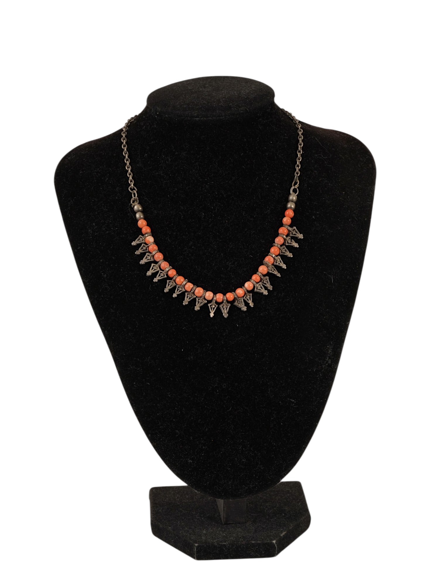 ANTIQUE TRIBAL STERLING SILVER CORAL BEADED NECKLACE: An antique ethnic tribal fringe necklace. The necklace features graduated salmon-pink and deep orange coral beads suspended with openwork silver triangular charms decorated with granulation and wirewo