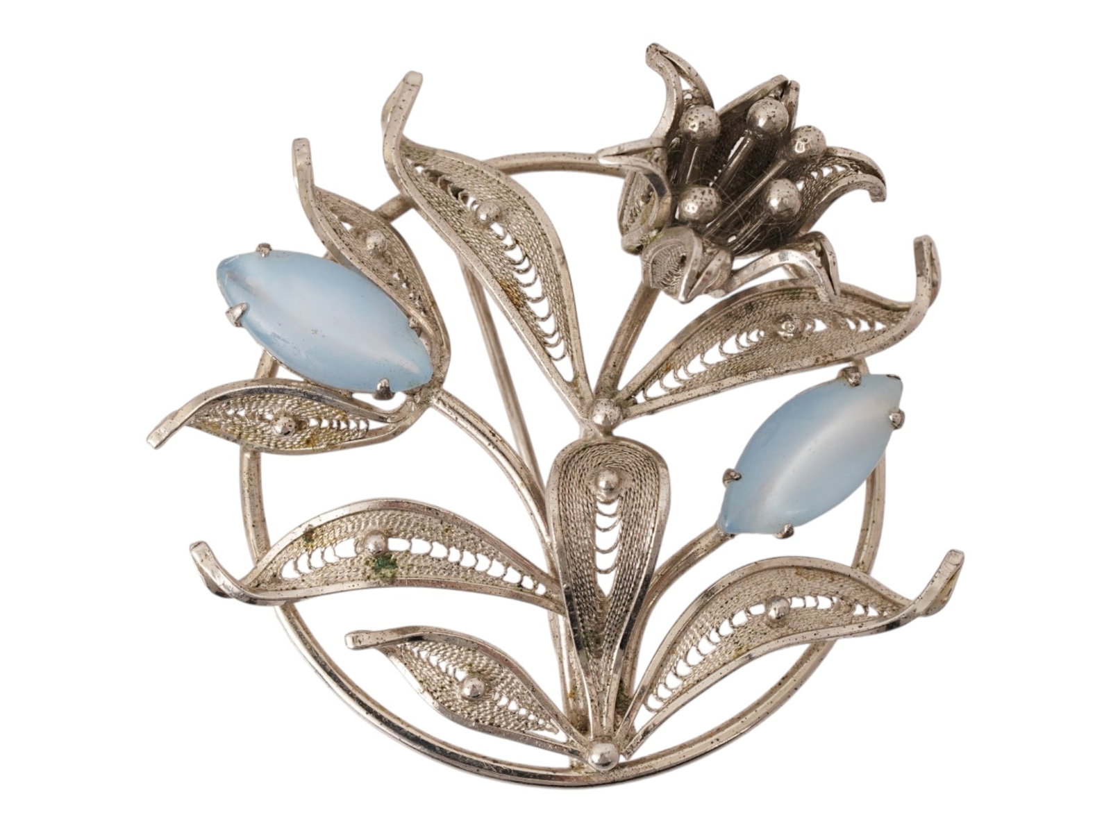 AMERICAN ENZELL STERLING SILVER FILIGREE FLORAL BROOCH: An American sterling silver brooch by Enzell. The ware features an intricate filigree design depicting a central blossoming flower flanked by two smaller buds. The buds are set with light blue cabocho