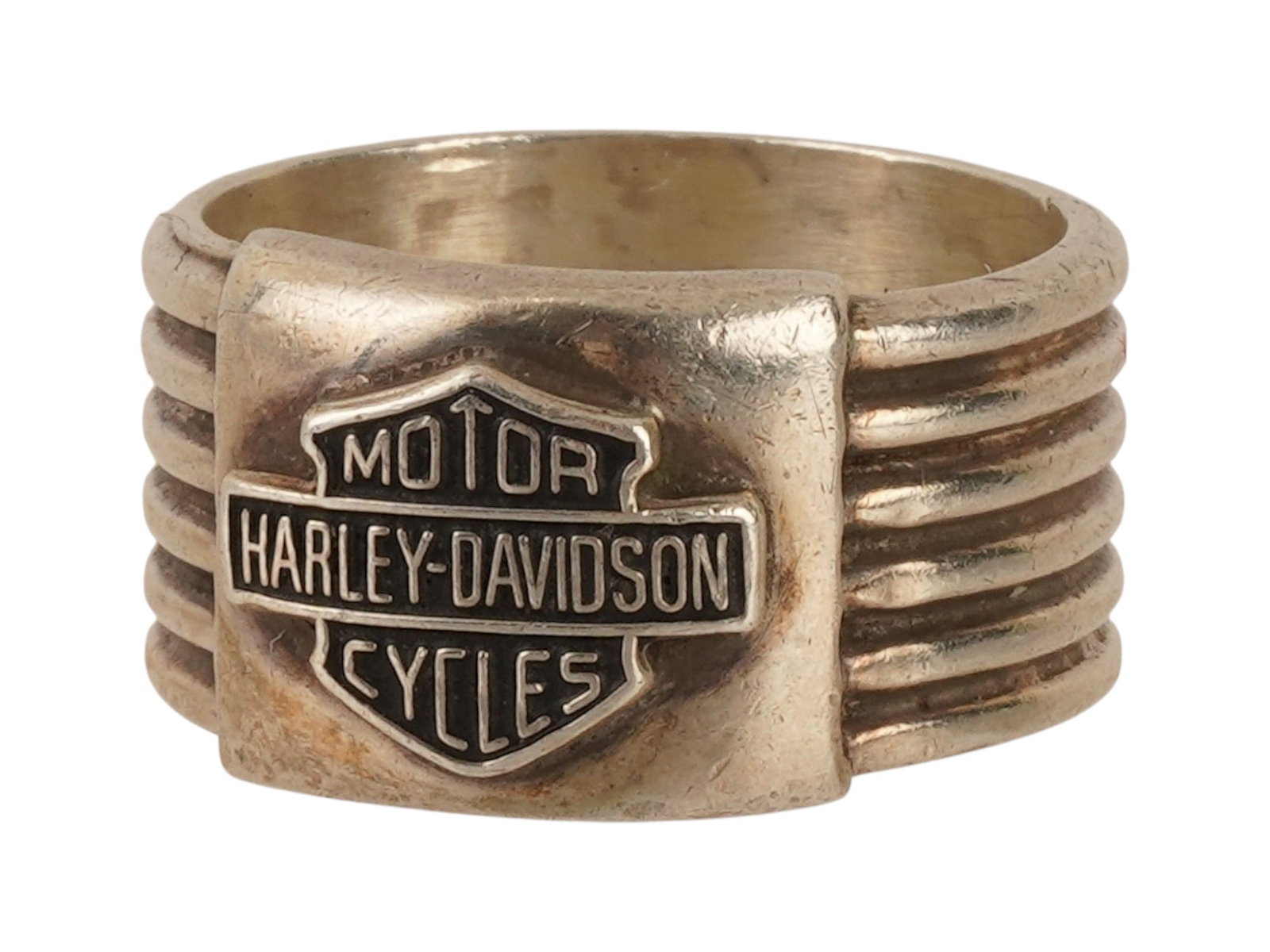 HARLEY DAVIDSON STERLING SILVER BAR SHIELD LOGO RING: A sterling silver ring featuring the iconic Harley Davidson Bar and Shield logo centrally positioned on a wide, textured band. The shank is designed with six horizontal parallel ridges. The interior o