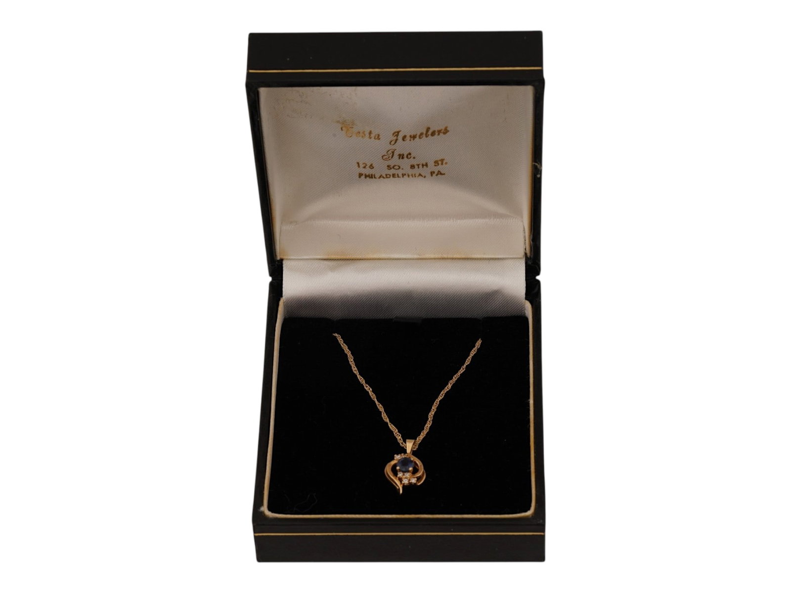 VINTAGE 14K YELLOW GOLD SAPPHIRE AND DIAMOND NECKLACE: A vintage 14K yellow gold sapphire and diamond necklace featuring an elegant ribbon-form pendant. The design centers on a round blue sapphire accented by a curved line of sparkling diamond accents wit
