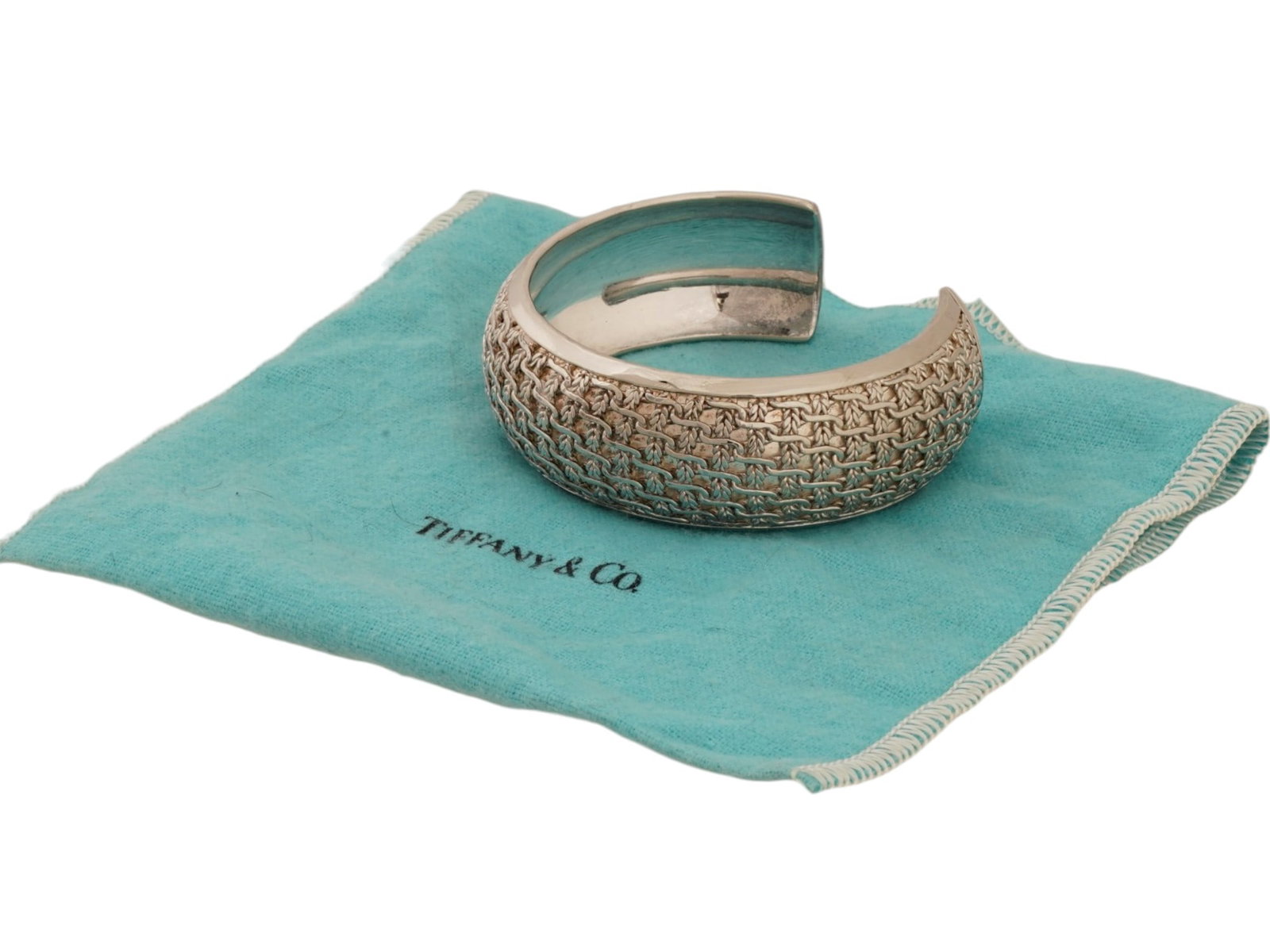 TIFFANY AND CO STERLING SILVER WOVEN CUFF BRACELET: A vintage sterling silver cuff bangle bracelet by Tiffany and Co. Relief woven or basketweave design. Marked T. and Co., 925 inside. Weight: 45 g. The item comes in original pouch. Luxury Jewelry And 