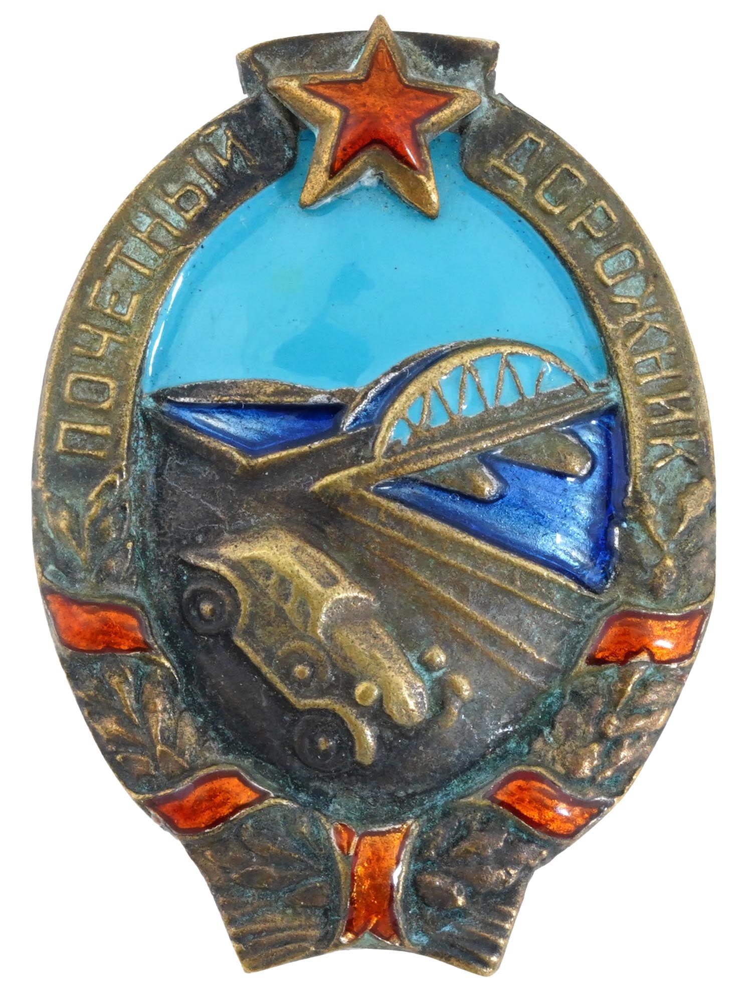 RUSSIAN SOVIET HONORARY ROAD WORKER ENAMELED BADGE: A Russian Soviet Honorary Road Worker enameled badge. In the center of the sign is a relief image of a road with a moving car and a road bridge in the background. Placed in a wreath tied with a red en