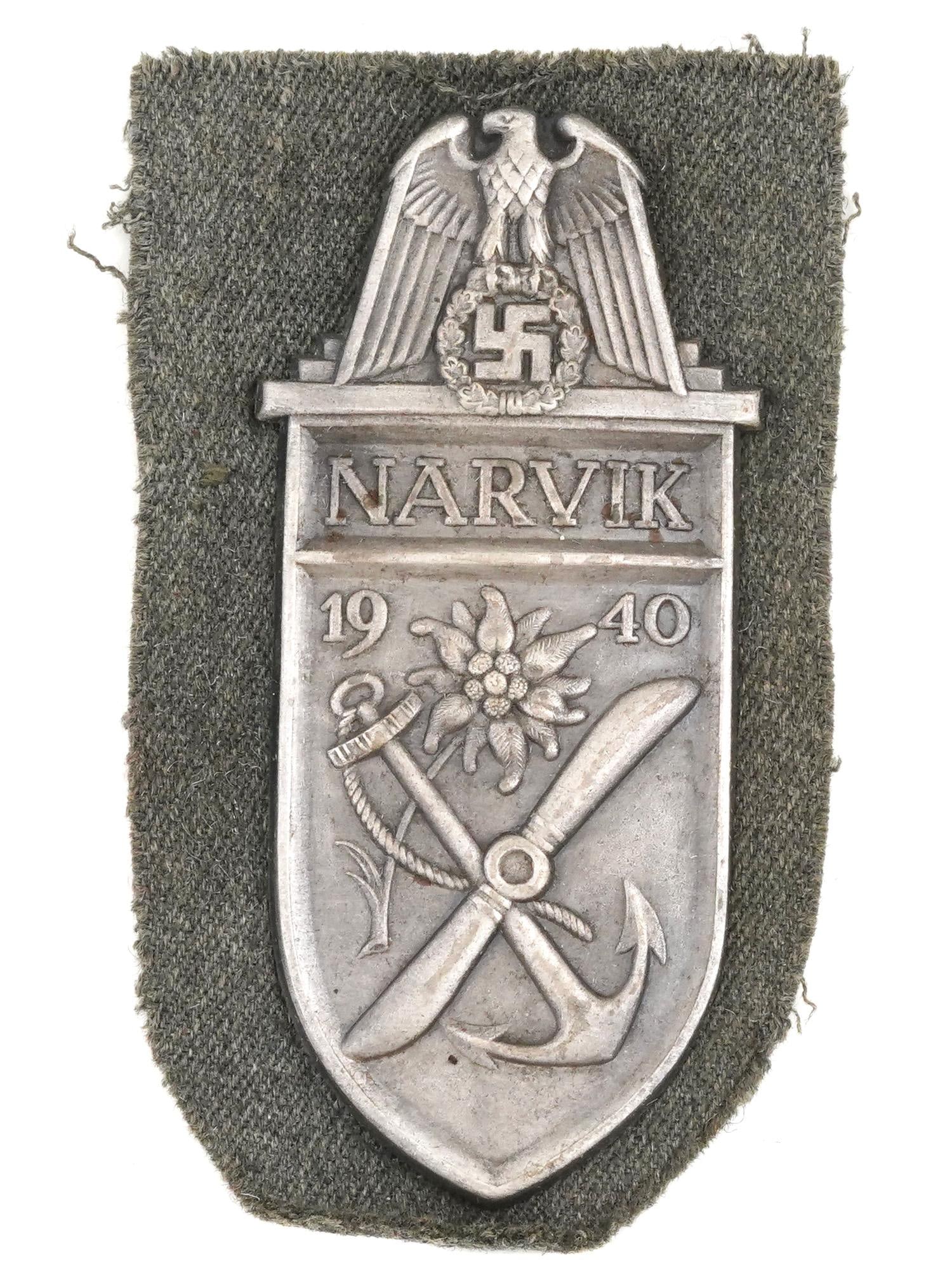 WWII NAZI GERMAN NARVIK SHIELD MILITARY BADGE: A World War II Nazi German Narvik Shield, a military decoration worn on the upper left sleeve of the tunic and awarded to all German forces that took part in the battles of Narvik between 9 April and 