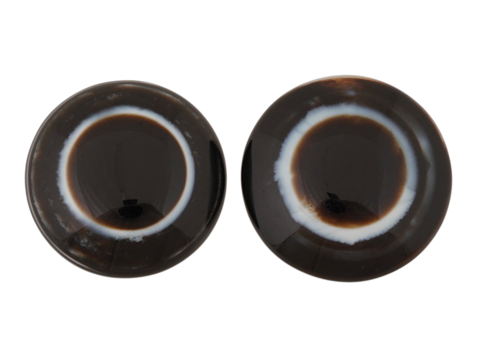 PAIR OF NATURAL BULLSEYE BANDED AGATE CABOCHONS: A pair of natural bullseye banded agate cabochons. The polished stones display concentric bands in shades of brown, black, cream, and white, creating the distinctive eye pattern. Natural Gemstones And