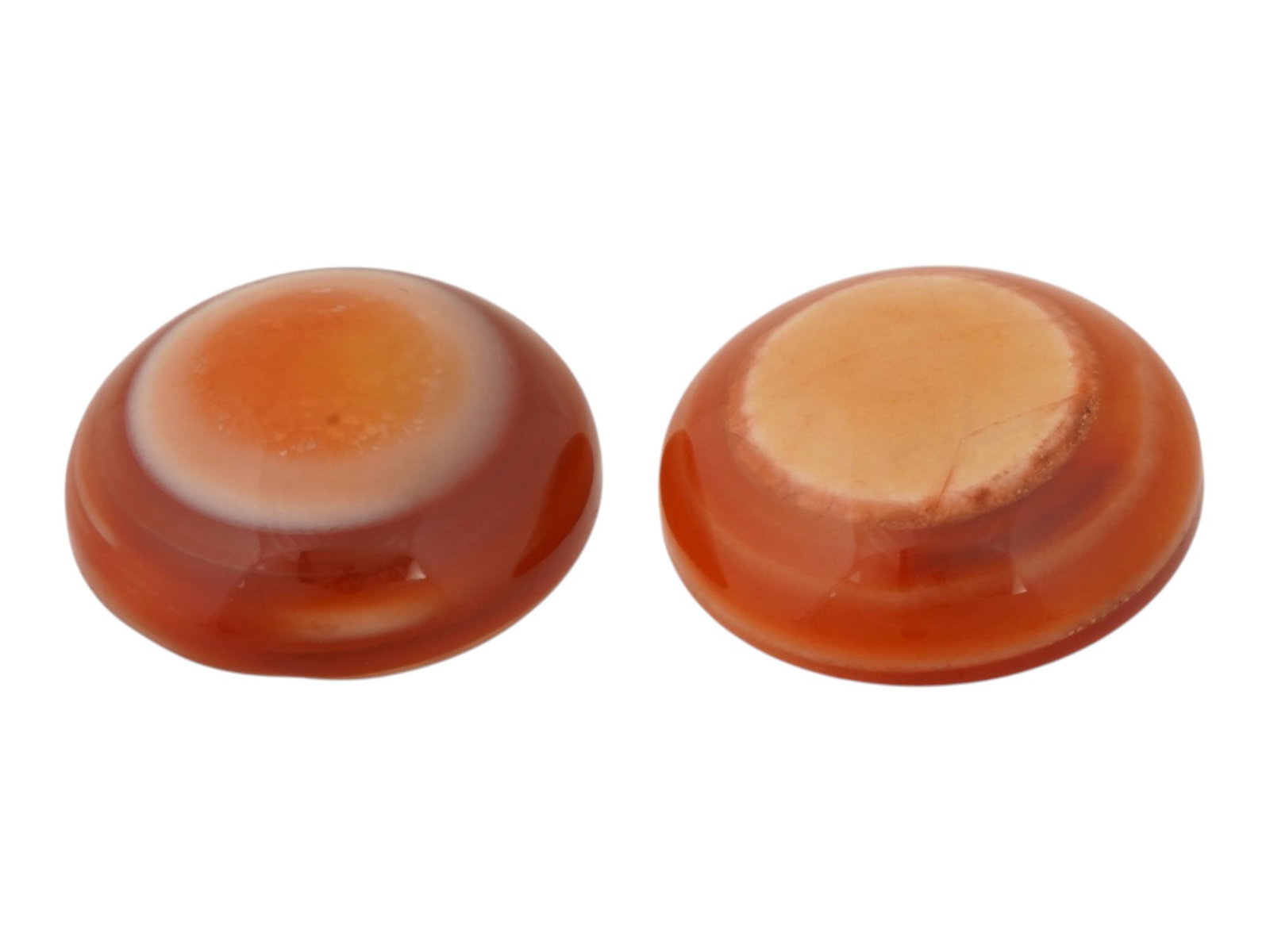 PAIR OF POLISHED BANDED CARNELIAN AGATE CABOCHONS: A pair of polished banded carnelian agate cabochons. The natural gemstones display concentric banding in warm orange, red, cream, and white tones, with flat reverse sides indicating they were cut for 