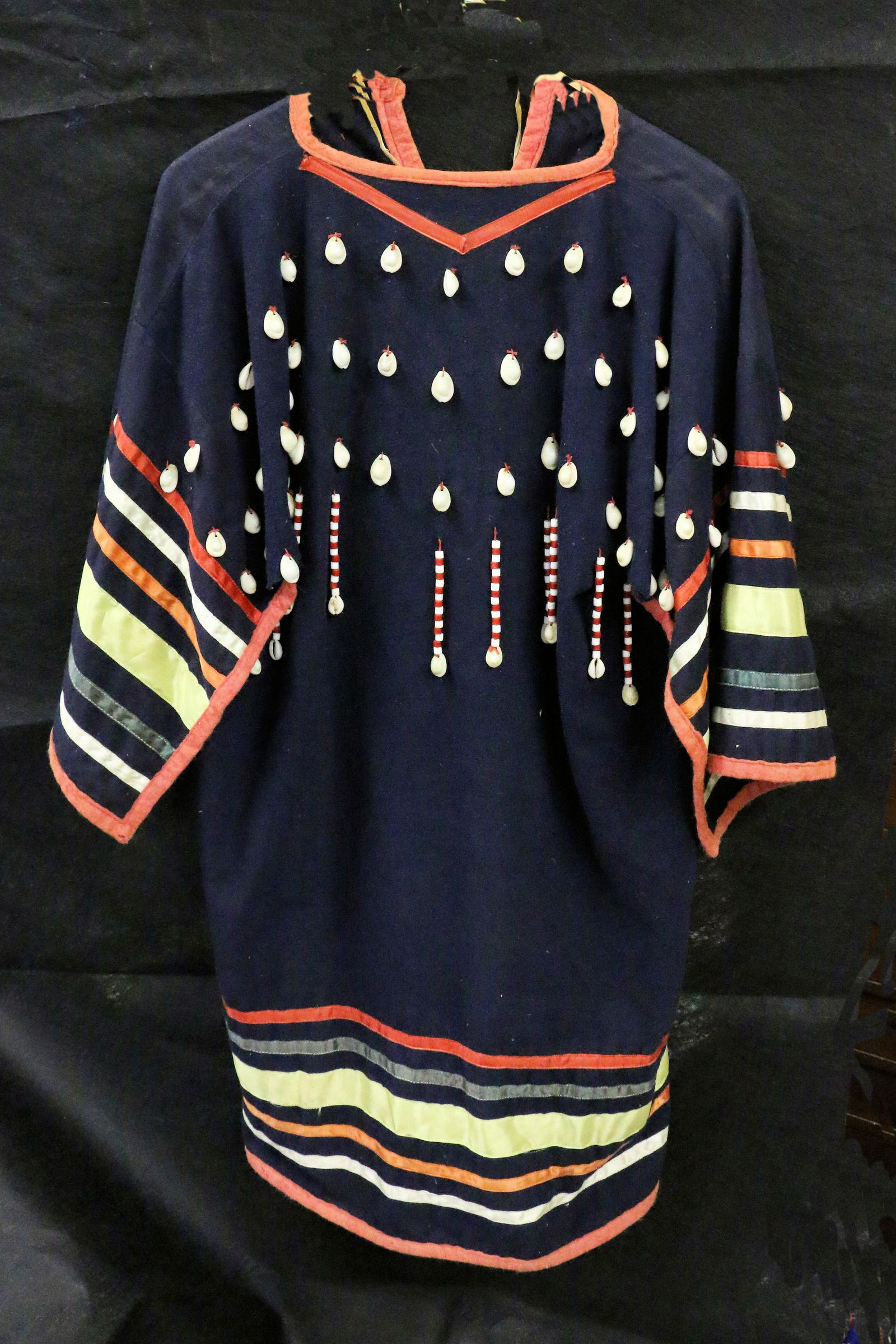 Sioux Plains Woman Dress: Sioux Plains Woman Dress embellished with cowrie shells and silk strips and faded red felt trim, 38.75" long, twisted cordage.